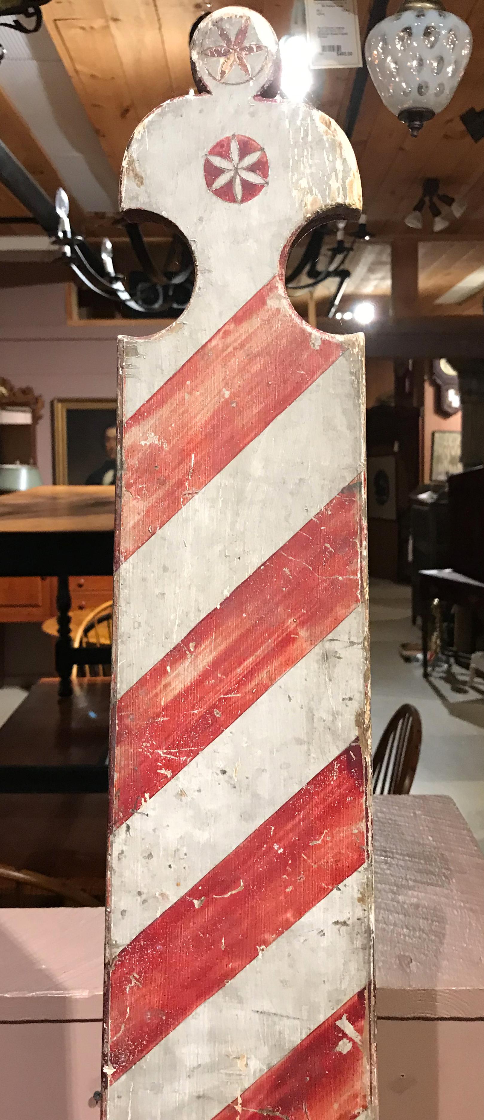 A wonderful polychrome wooden shaped barber pole folk art advertising sign of Cape Cod origin, probably circa 1850, attached to a newer custom ebonized wooden base, 19th century. Good overall condition, with some paint loss and fade. Dimensions: