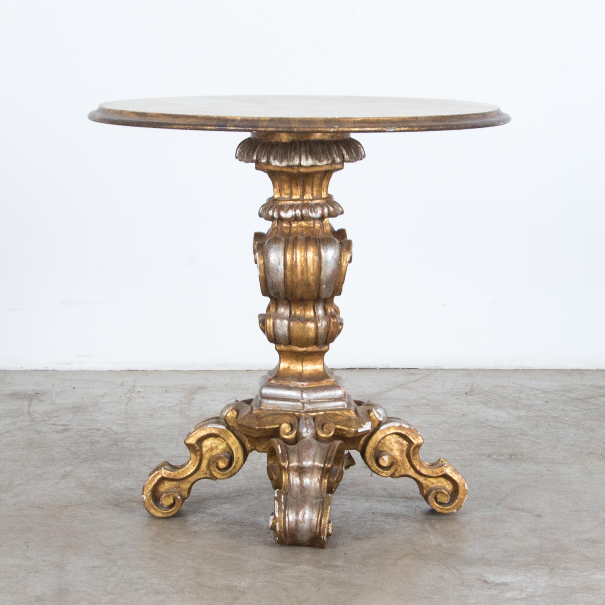 A Baroque inflected wood carved table from Italy, circa 1950. Brightly painted in metallic hues, this piece is an eclectic vintage interpretation of Rococo fashion. Executed with traditional techniques, hardwood is elaborately carved into scrolling