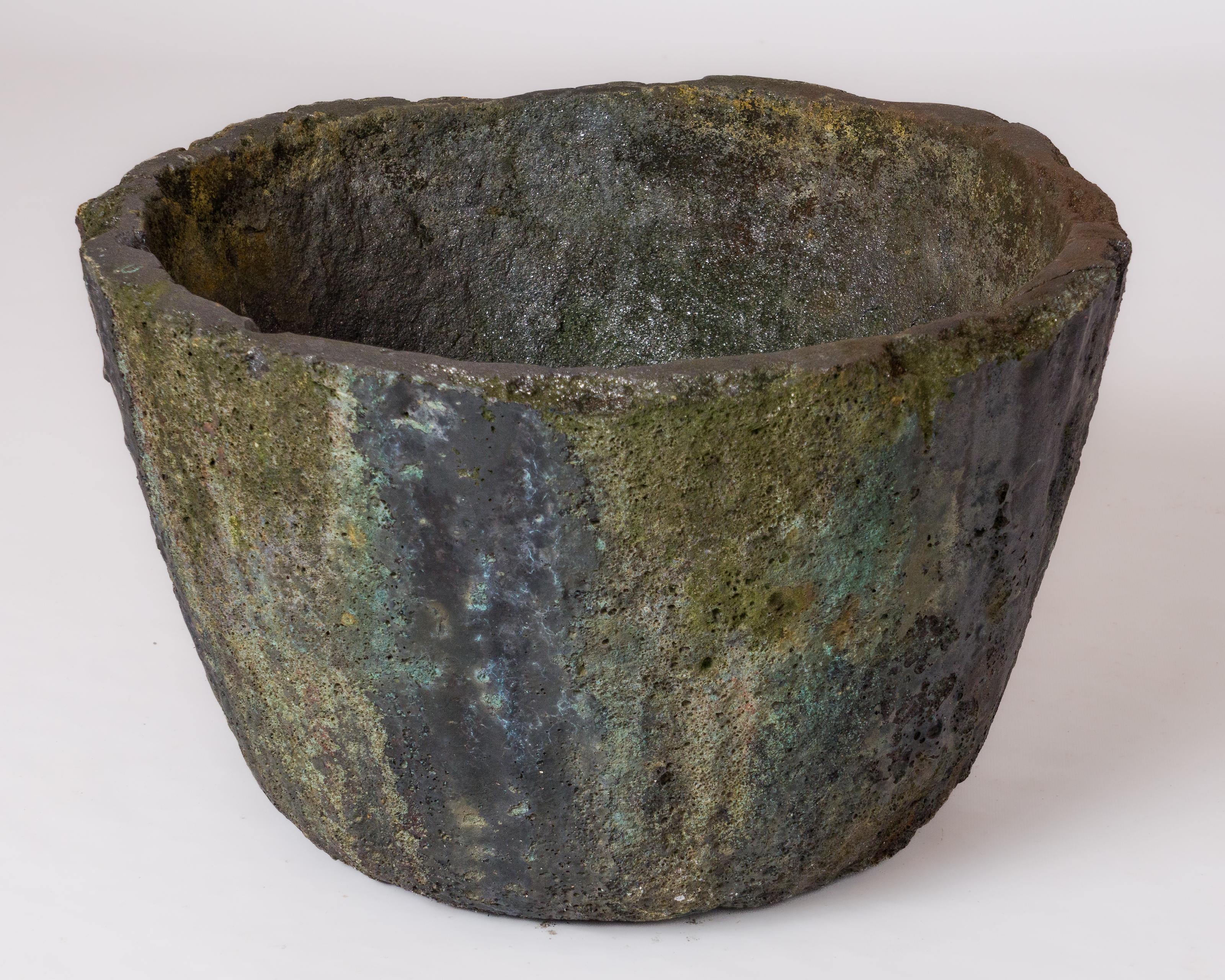 Lava rock crucible from the 1950s, suitable for outdoor use, particularly as a planter. A hole was drilled for this purpose to allow water to drain.
The metal drips have left polychrome traces with iridescent accents on all exterior