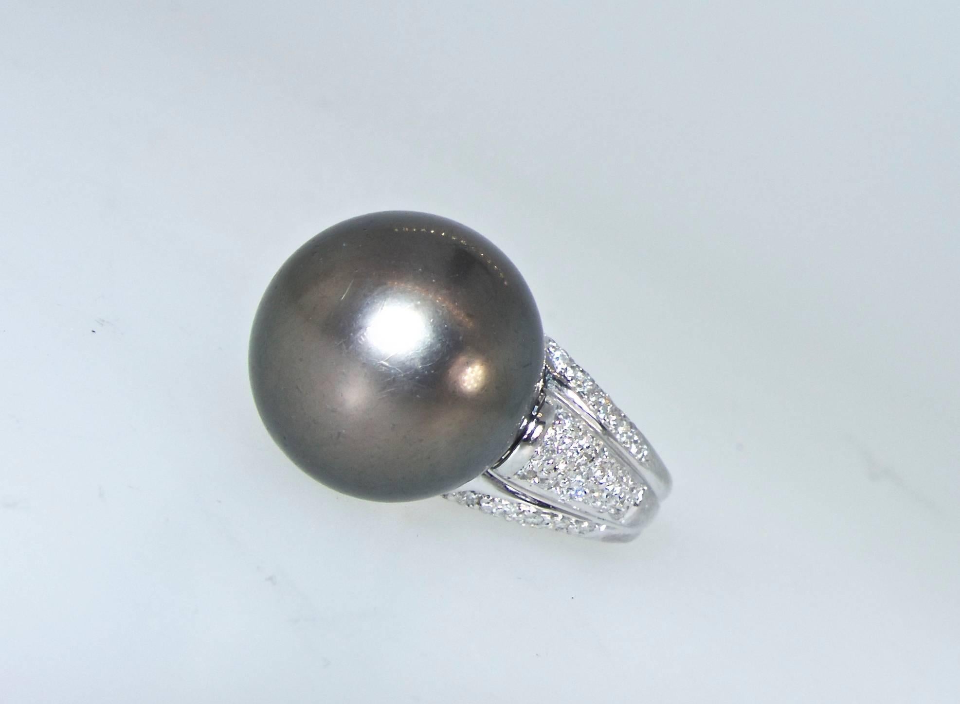 From Tahiti comes an iridescent silver black fine pearl of 14.87 mm - displaying a smooth surface.  It is a hair more than .50 inches wide perched upon a ribbed mound of approximately one carat of fine white diamonds - near colorless (H) and very