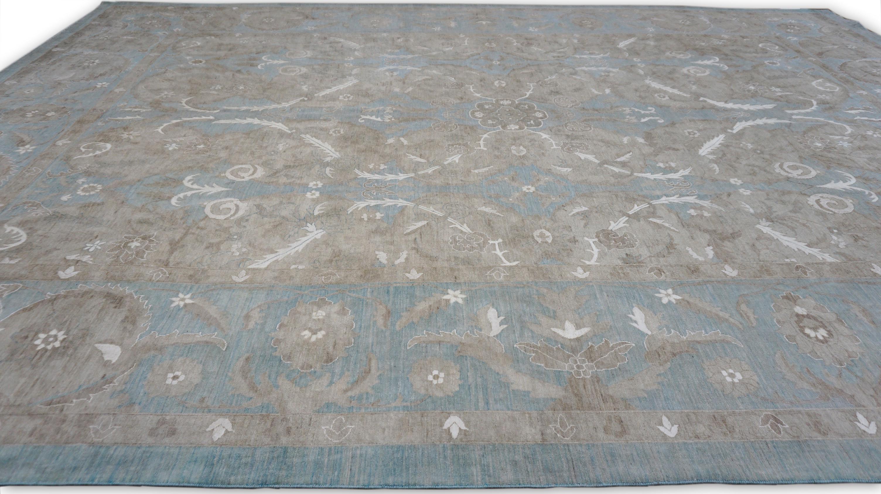 Esta alfombra de lana y seda anudada a mano presenta un exquisito diseño floral de inspiración persa, meticulosamente tejido en una delicada paleta de suaves azules, topos, tostados y blancos. El intrincado motivo simétrico muestra gráciles
