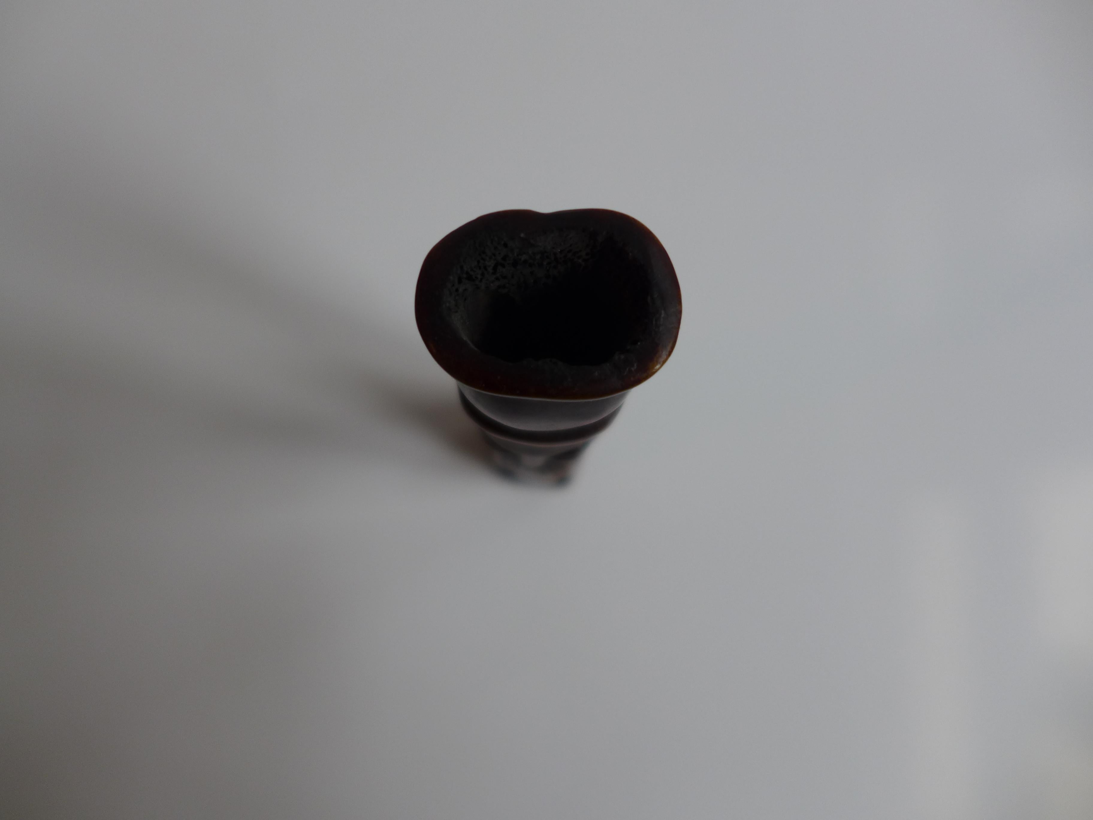 This Polynesian Tiki figure, carved from dark hardwood, depicts a human-like spirit with both hands covering its mouth, symbolizing silence, secrecy, and spiritual protection. The figure is hollowed, a traditional technique that lightens the piece