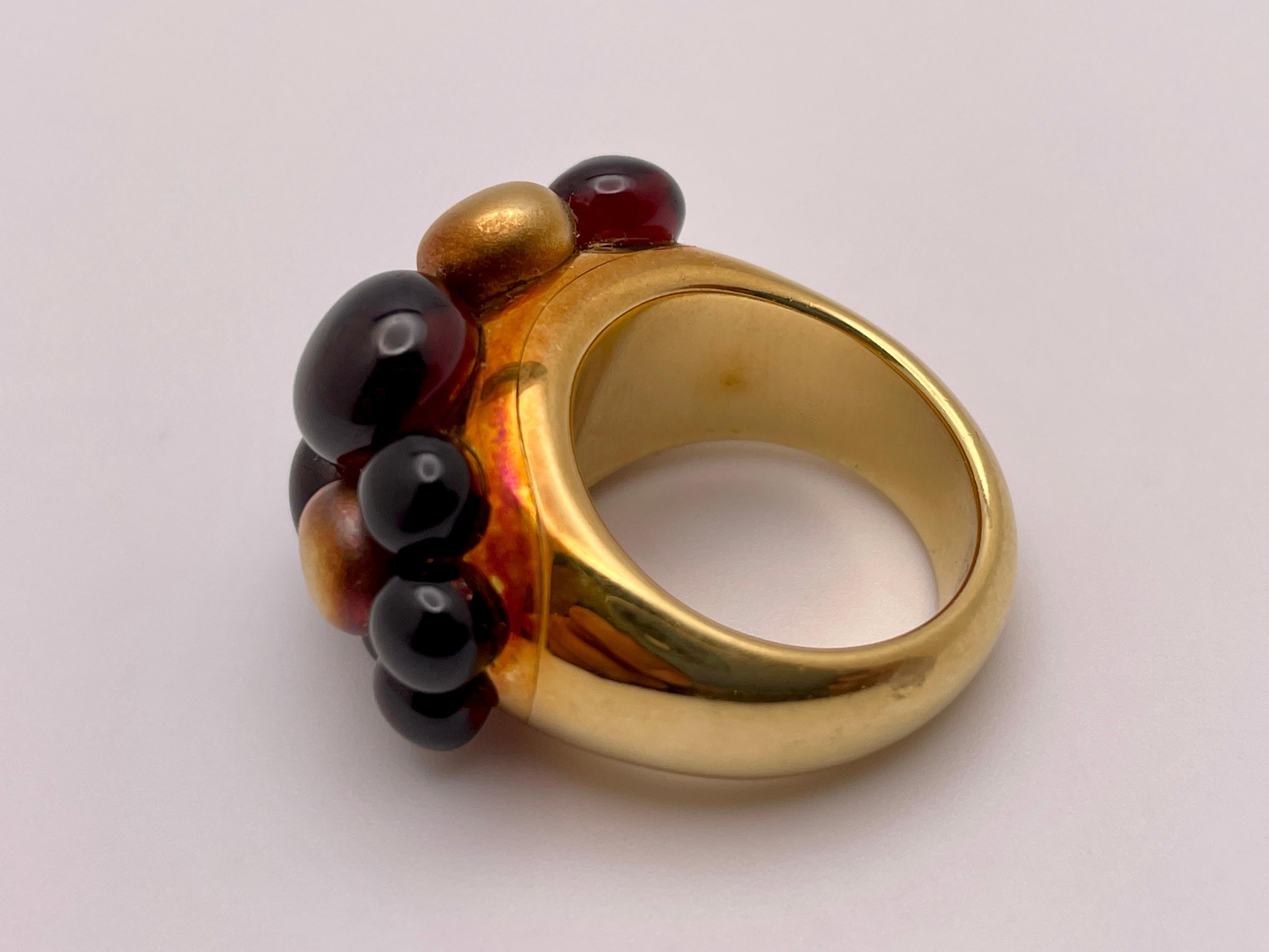 An authentic 18K yellow and red gold Pomellato color stone ring. Set with 11 cabochon round garnets, weighing approximately 15 CT,  throughout which three golden nuggets are scattered. This beautiful ring has a gross weight of 32 grams, and is a