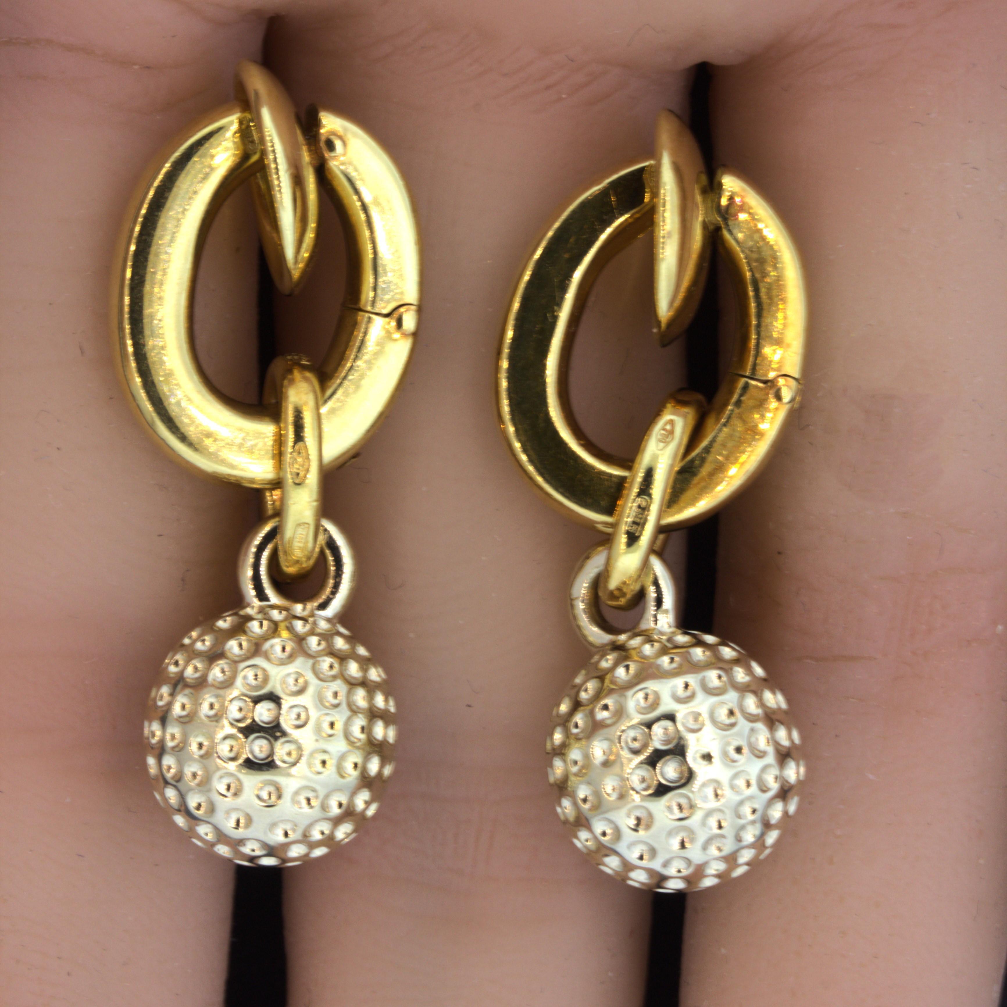 An original piece by Italian designer Pomellato. The earrings feature classic huggies which have a unique twist to them. There is a drop portion with a dotted gold sphere that dangles from the huggies. Made in 18k yellow gold and signed Pomellato,