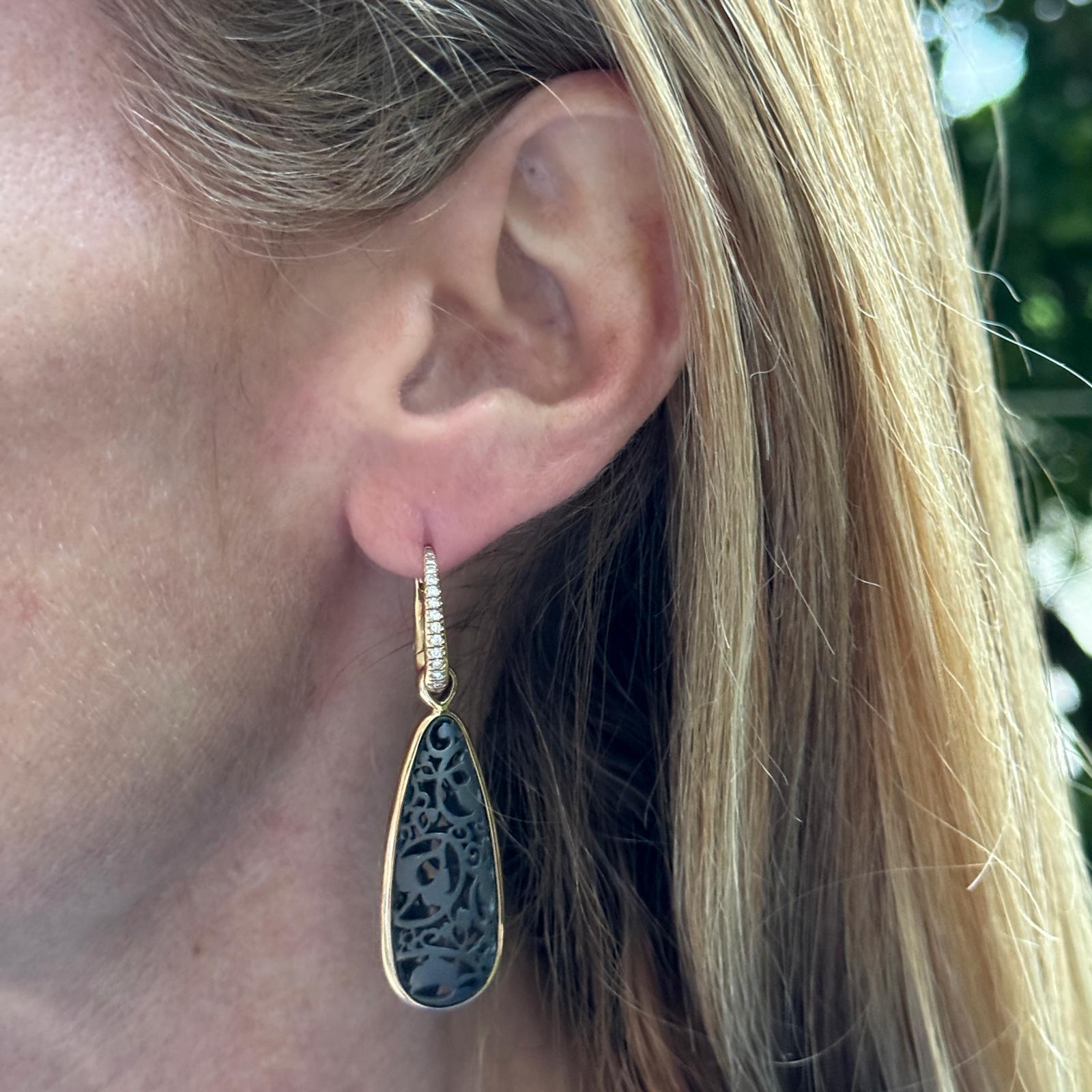 Pomellato modern diamond drop earrings crafted in 18 karat yellow gold and black titanium. The teardrop shape earrings feature 26 round brilliant cut diamonds weighing approximately .25 carat total weight. The earrings measure 2.25 inches in length.