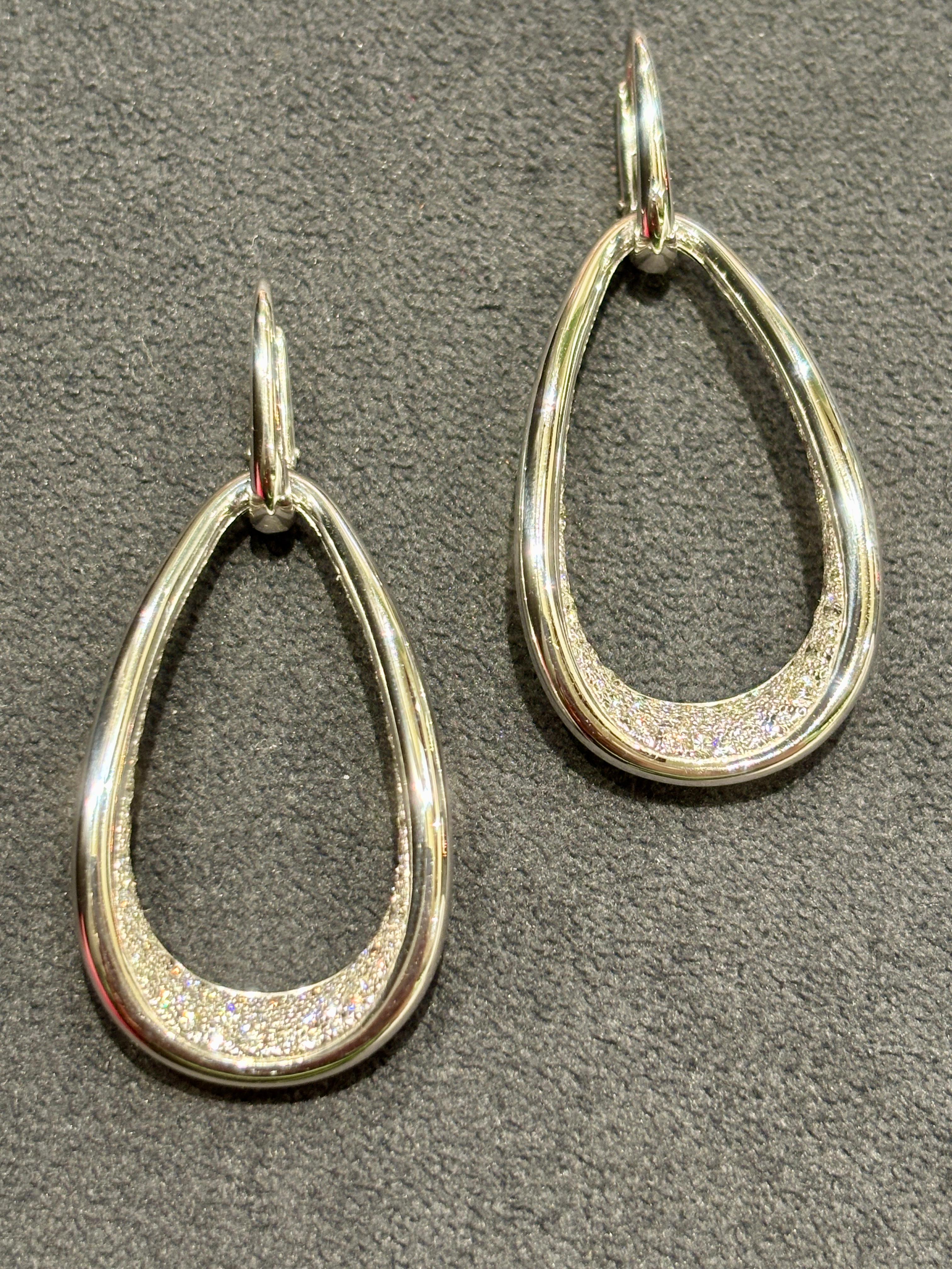 Questi eleganti orecchini di Pomellato pendono asimmetricamente come mostrato nelle fotografie. Sono realizzati in oro bianco 18 carati e la loro forma è accentuata da diamanti a taglio rotondo. 