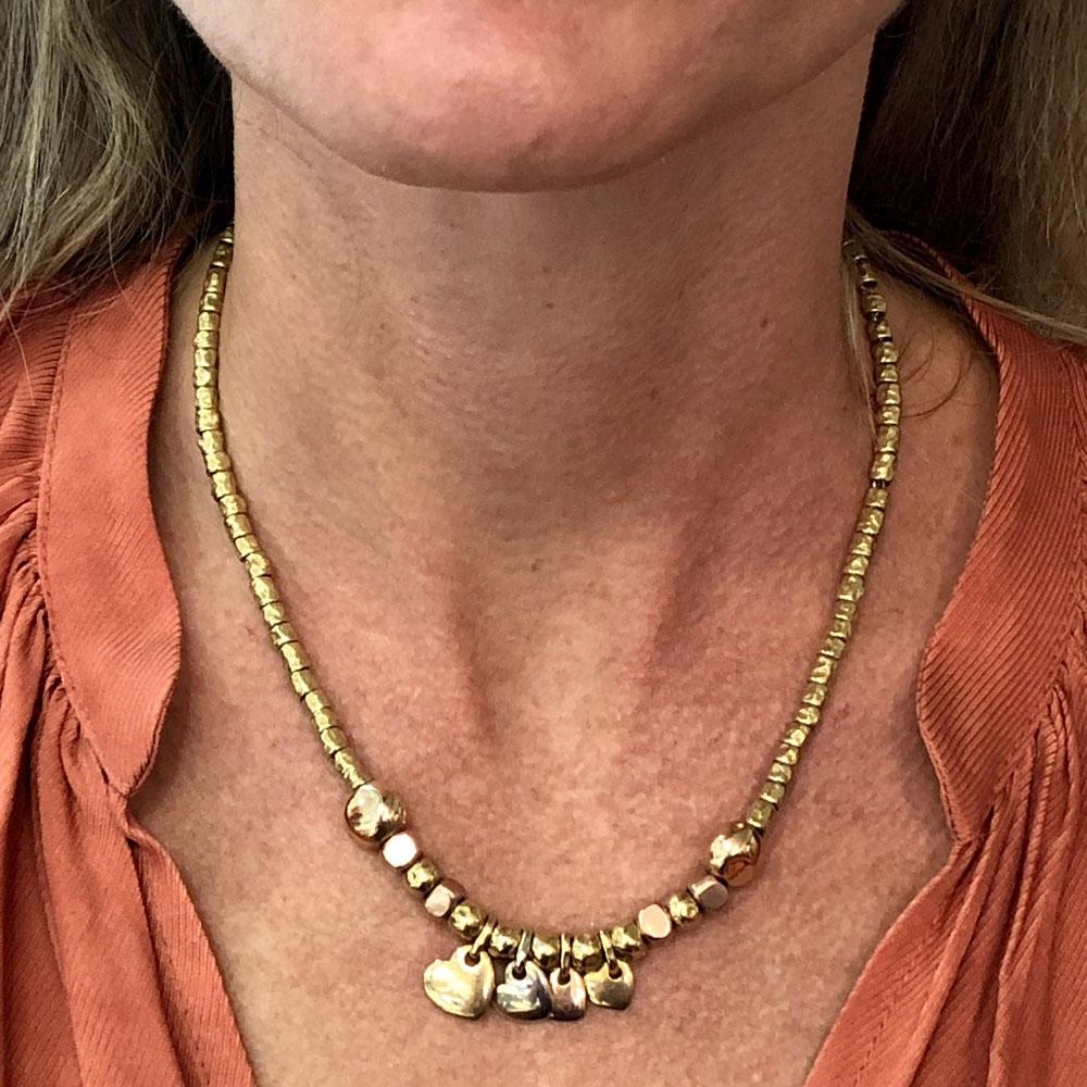 Pomellato 18 karat yellow gold necklace features rose gold and yellow gold heart pendants and charms. The necklace is part of the Dodo collection.The links and charms are all 18 karat gold and are strung on an unseen underlying sterling silver