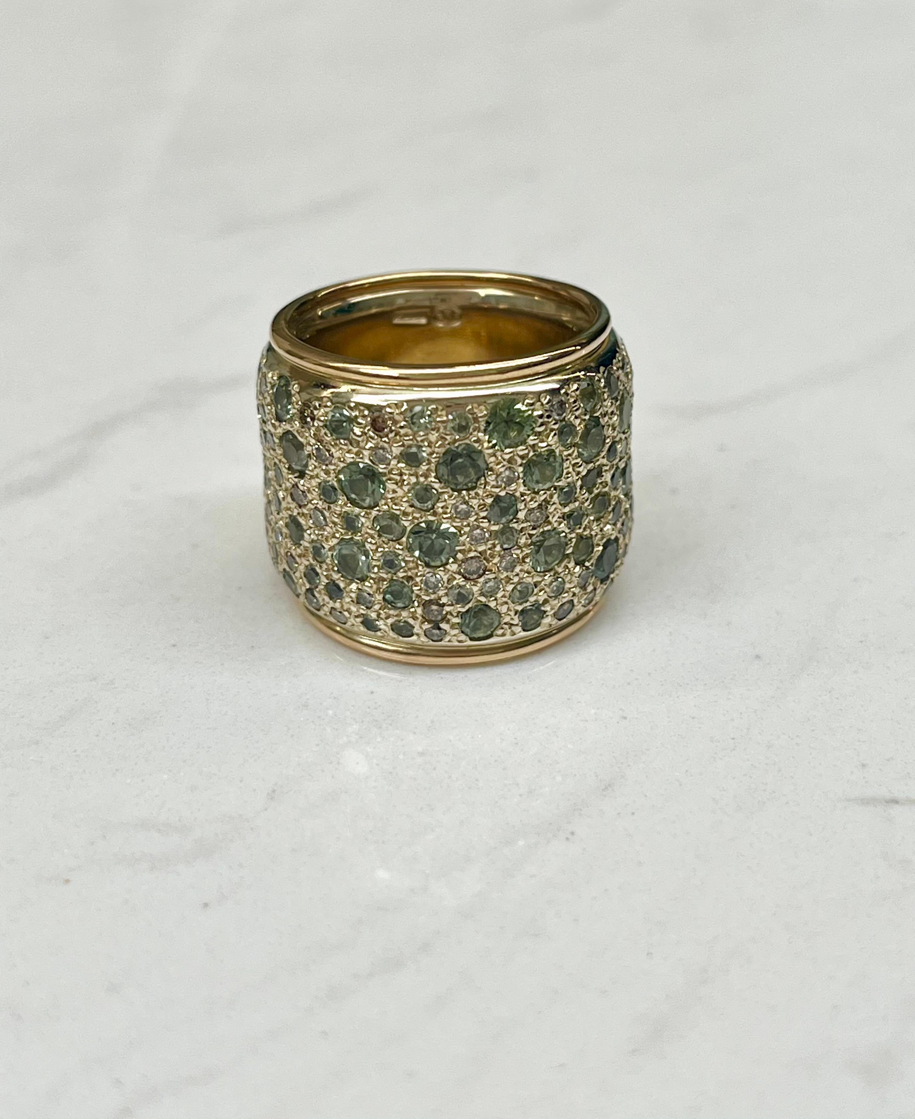 Erhöhen Sie Ihre Schmucksammlung mit dem exquisiten Ring mit breitem Band aus grünem Saphir und Diamant von Pomellato, einem wahren Meisterwerk an Luxus und Raffinesse. Dieser aus glänzendem 18-karätigem Gelbgold gefertigte Ring strahlt zeitlosen