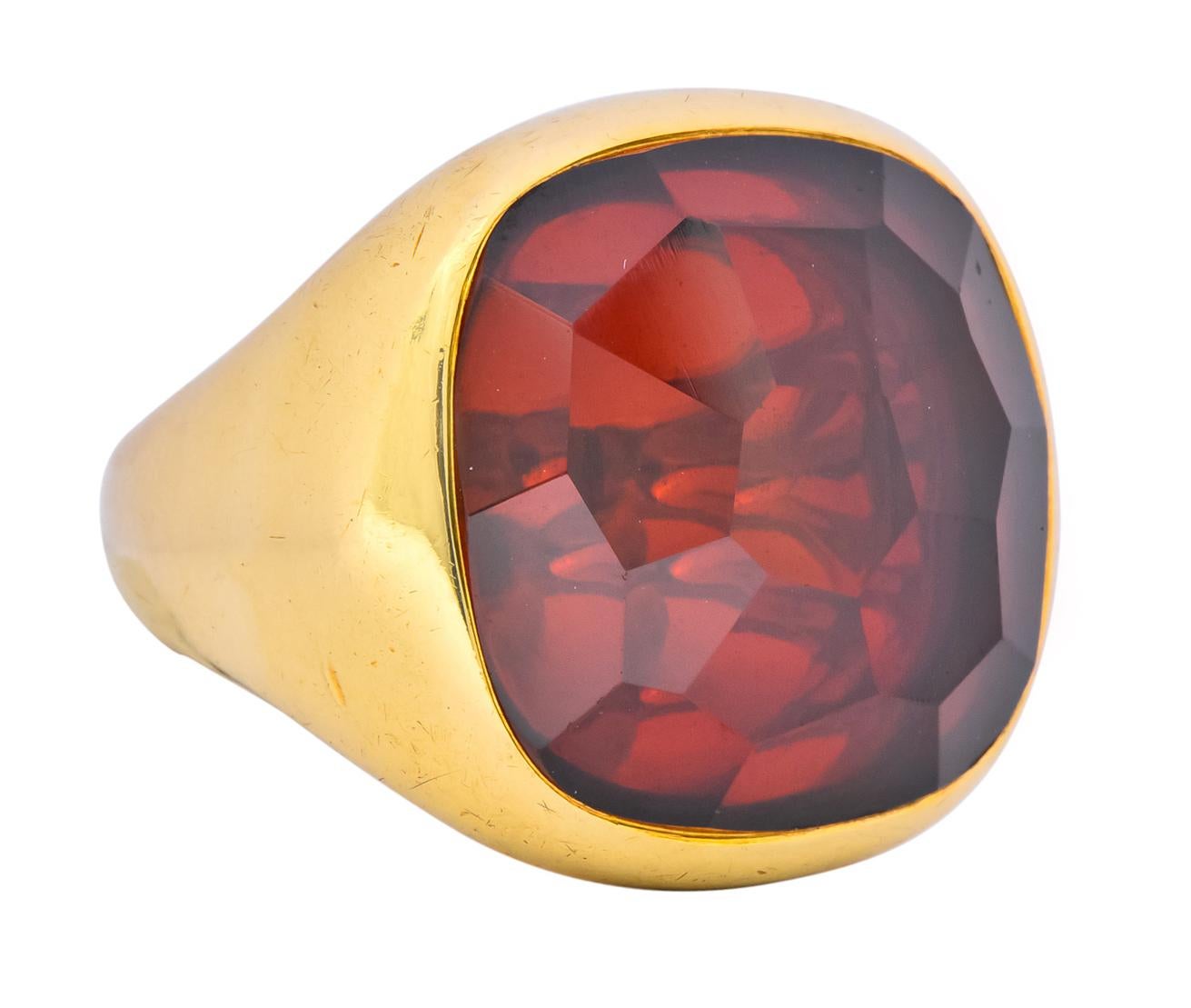Featuring a cushion cut garnet, faceted throughout, transparent and a rich wine red

Bezel set in a bold, highly polished gold mounting

Marked 750 for 18 karat gold and fully signed Pomellato 

Circa 2000

Top measures: 21.25 mm and sits 7.4 mm
