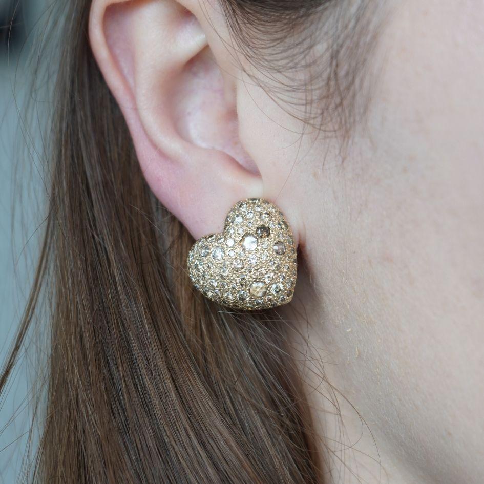 This pair of Pomellato Sabbia heart earrings is crafted in 18k yellow gold and set with a shimmering array of brown diamonds in mixed rose-cut and round brilliant-cut pavé settings. Designed in the shape of a full heart, each earring measures