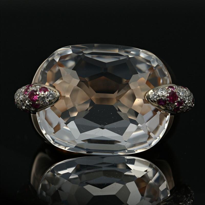 Sheer Italian glamour! Brilliantly imagined by Pomellato, this artistically designed cocktail ring is crafted in luxurious 18k yellow and white gold and showcases a white topaz solitaire kissed by berry red rubies and icy white diamond accents.    
