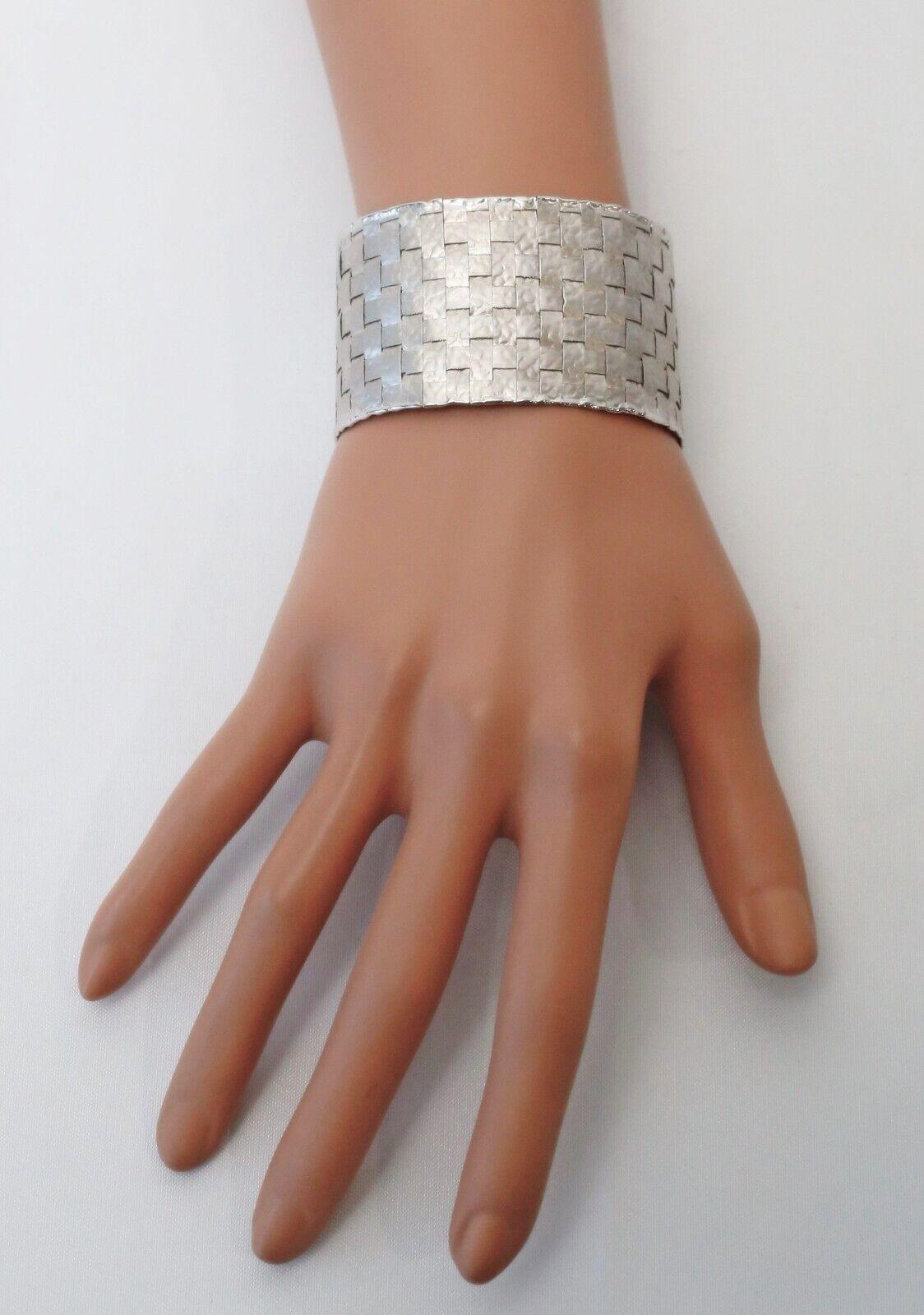 Esta llamativa pulsera ancha de oro blanco de 18 quilates de Pomi presenta un diseño de tejido de cesta con una bella textura que combina una audaz artesanía con una refinada elegancia. El acabado martillado realza la calidad reflectante del oro,
