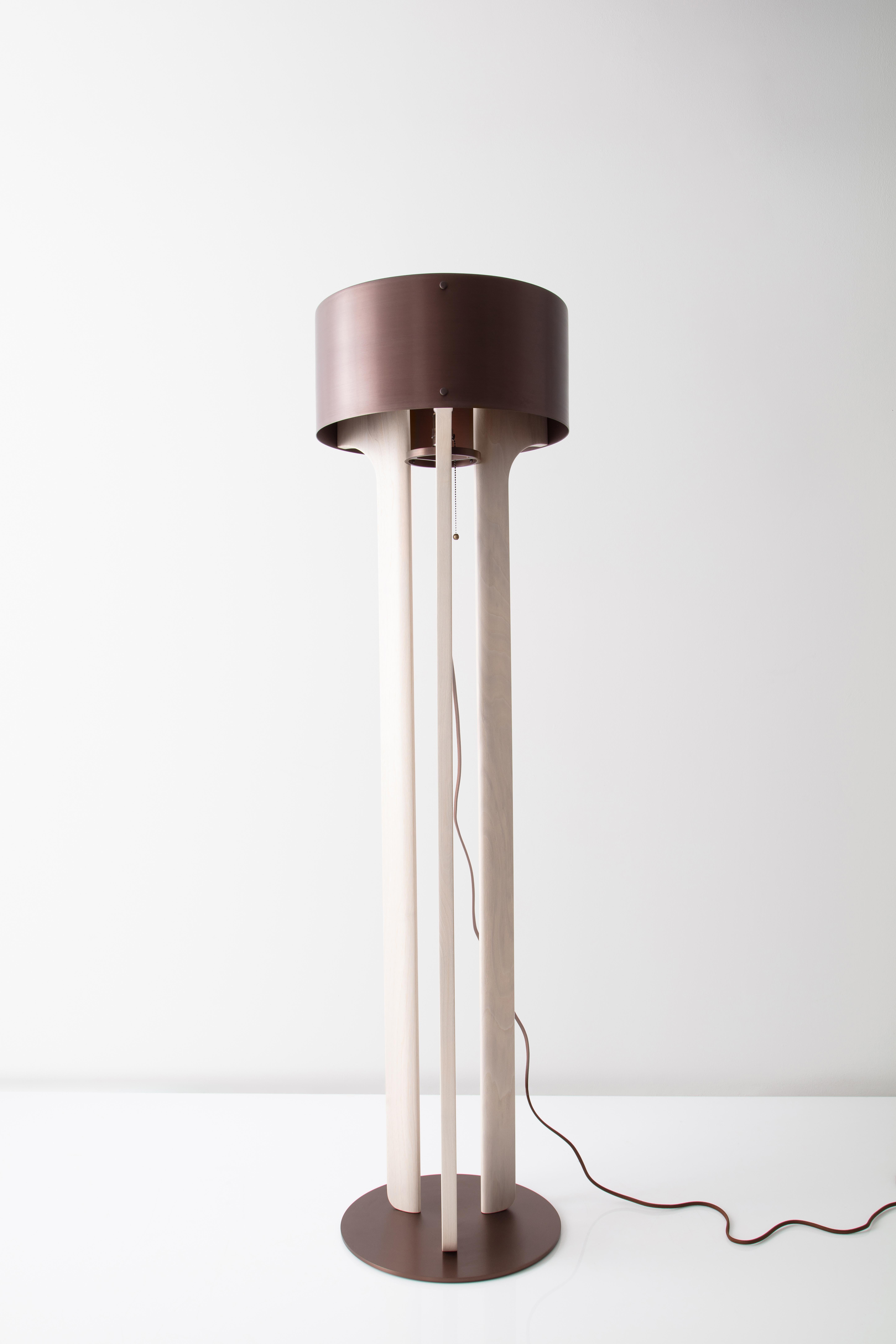 The Pommer floor lamp features a satin anodized drum shade with a trumpet-like interior. Warm white light radiates light from its core. Requisite LED bulb is supplied with the purchase of this fixture. The legs of the lamp are carved from solid wood