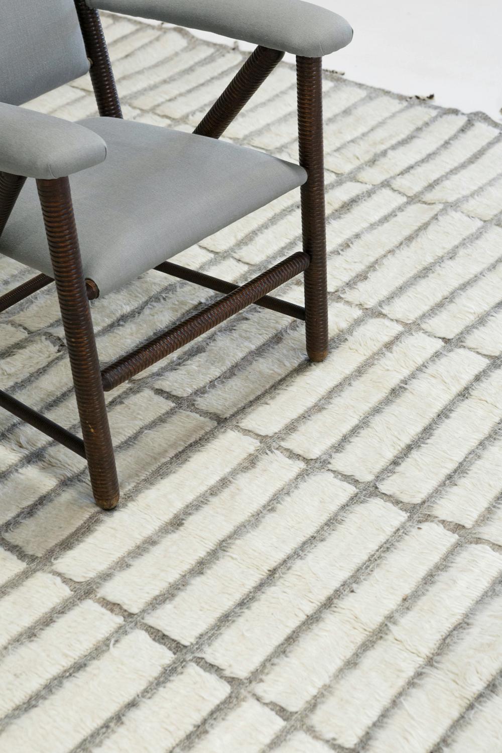 'Pommie' is made of handwoven luxurious wool rug with timeless embossed rectangular detailing. In addition to its gray flat weave, Pommie has a beautiful ivory shag that brings a lustrous and contemporary feel to one's space. The Haute Bohemian