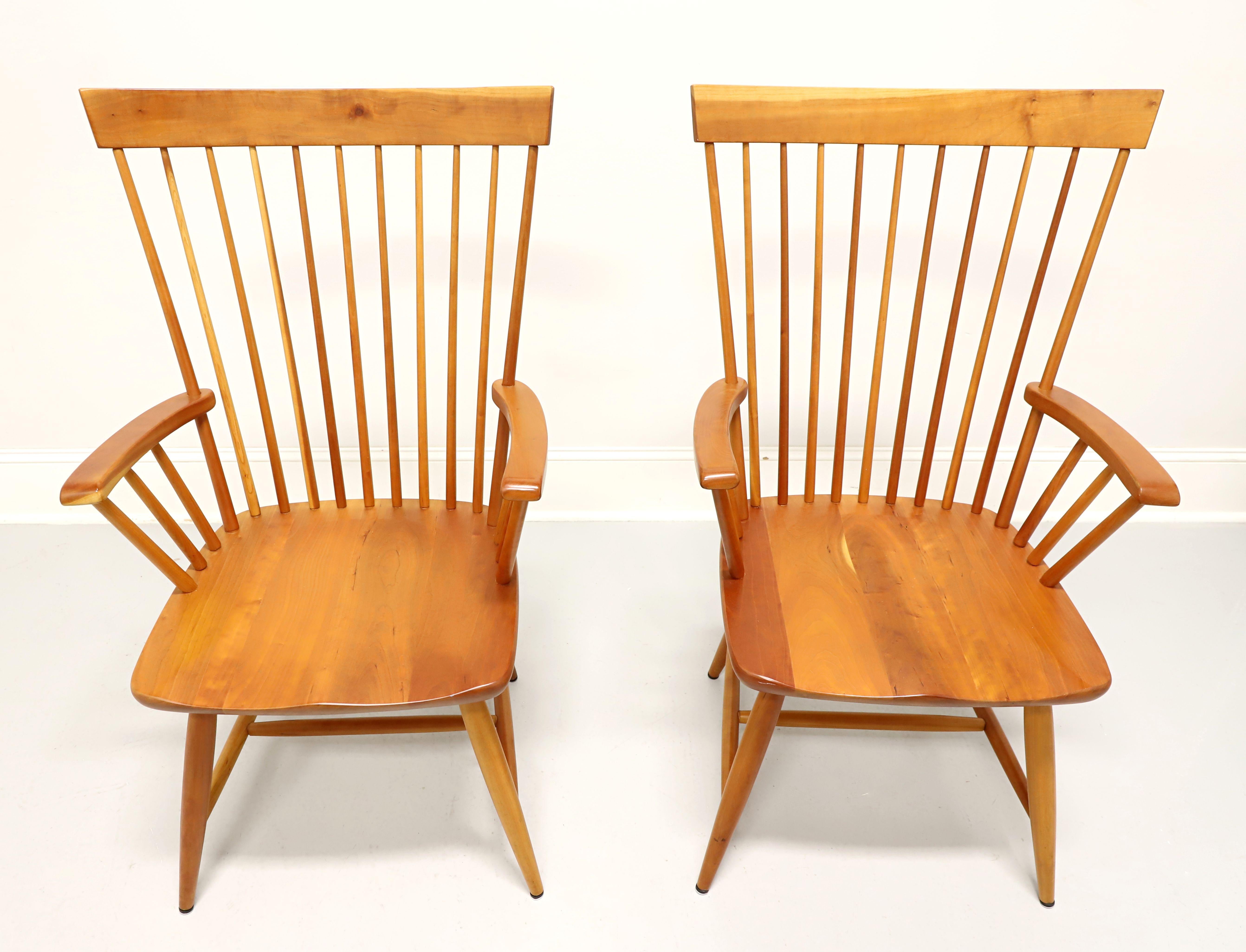A pair of Early American Windsor style dining armchairs by Pompanoosuc Mills, their Mason. Solid cherry wood with rectangular crestrail, tapered spindles backrest, gently curved arms, saddle shape seat, flared tapered legs and stretchers. Made in
