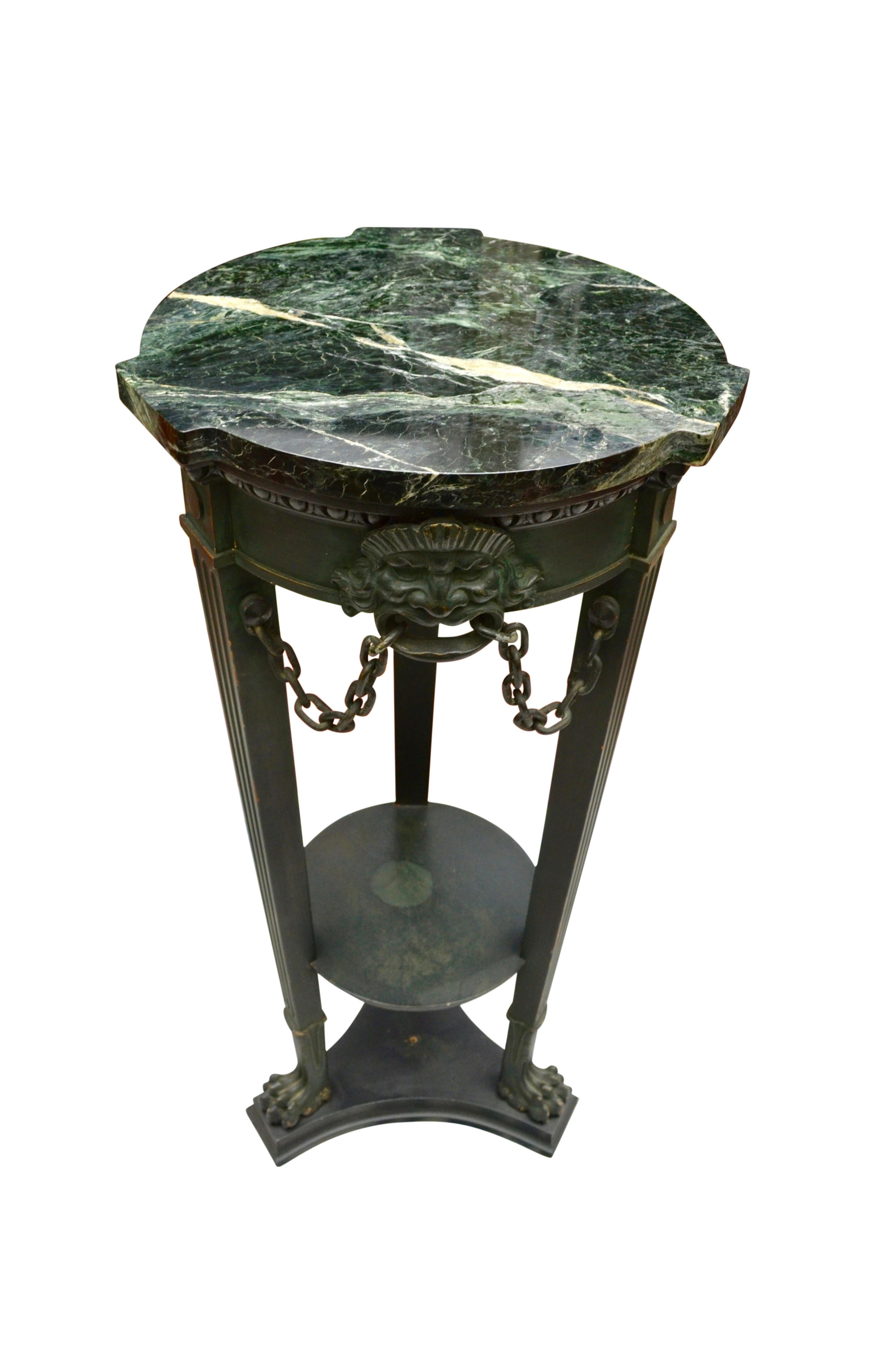 A classic painted wood marble and metal tri-pod pedestal modelled after an ancient pedestal discovered in Pompeii. Below the shaped green marble top are three metal grotesque masks which connect to the three legs with metal chains. The three fluted