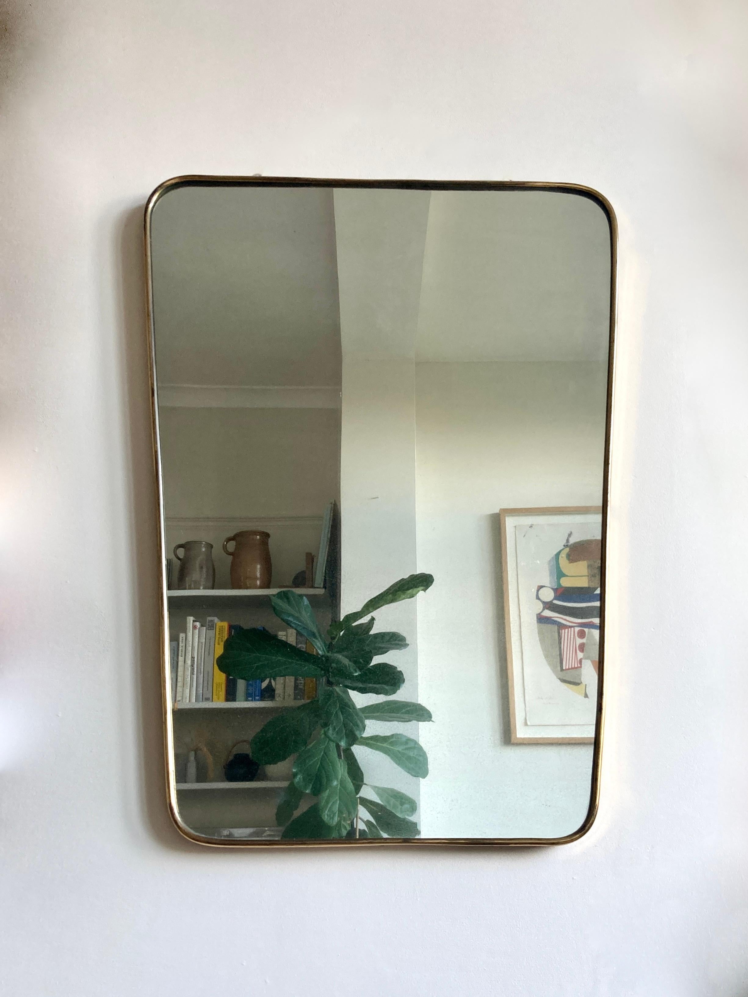 Vintage brass framed mirror from Italy in the manner of Gio Ponti, circa 1950. 

A beautifully simple design. The solid brass frame has gentle curves which flow seamlessly around the mirrored glass.

The mirror’s size and shape lend itself to