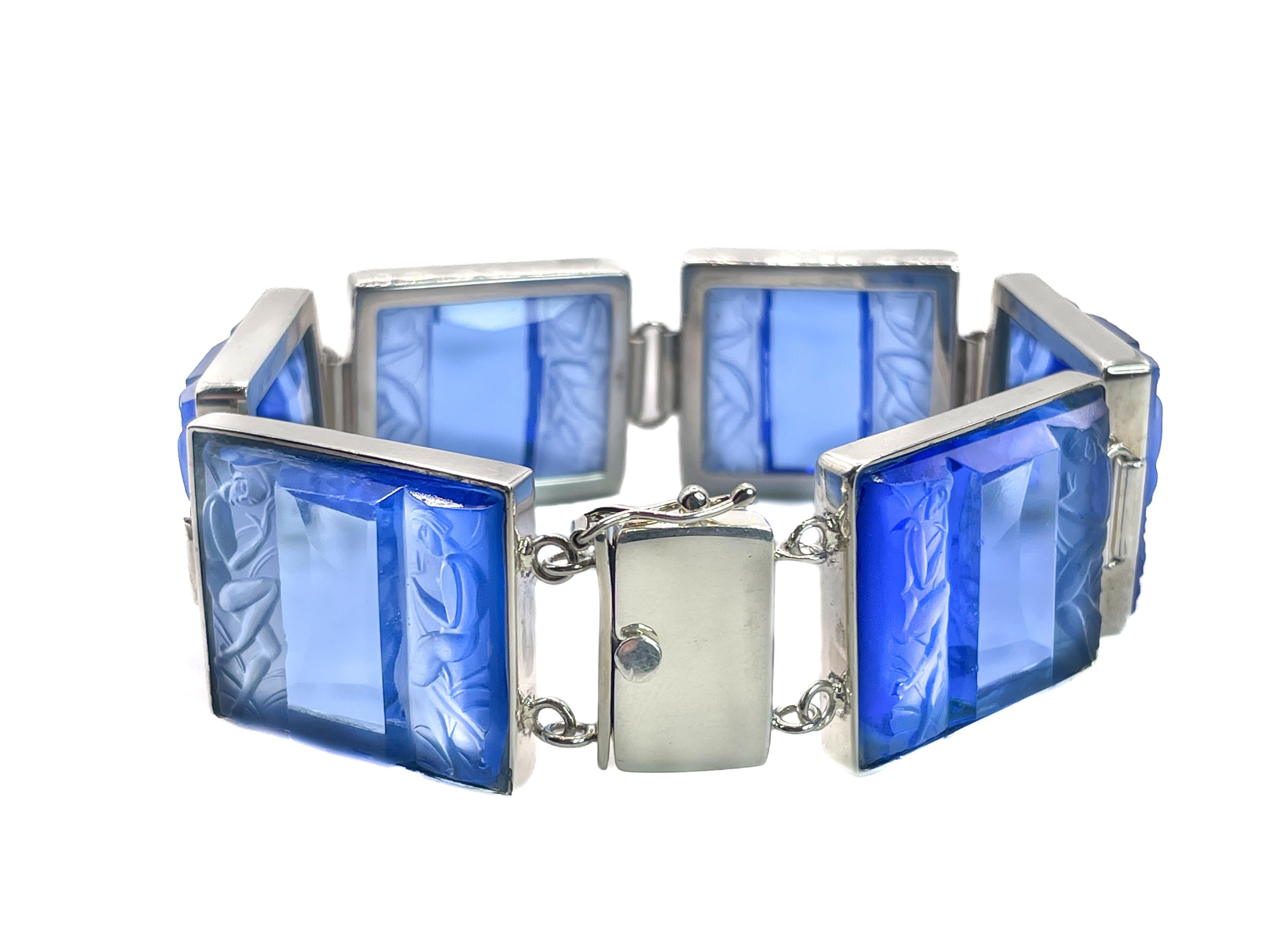 This timeless, glamour bracelet is made from original blue Art Deco glass panels. The glass features an elegant molded motif of two stylized Art Deco nude women. 

The Art Deco movement reflected a love of modernity, sleek lines, and graceful