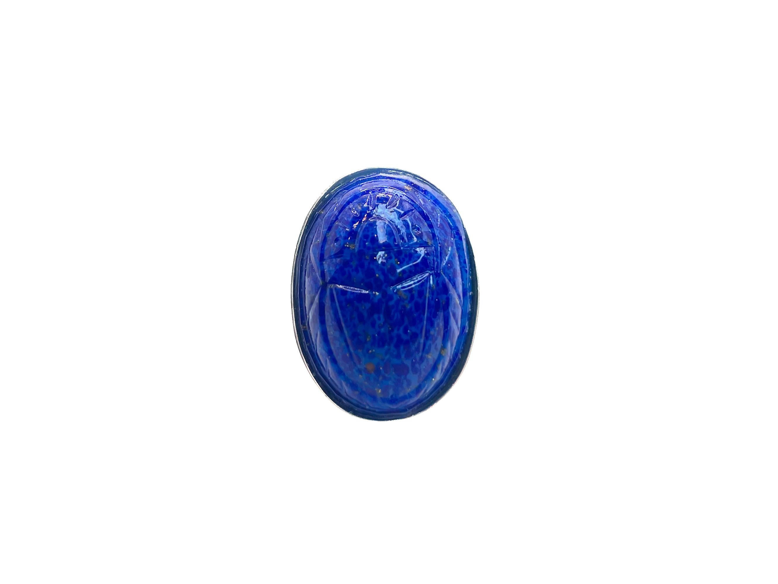 This Scarab ring is made from molded glass that is expertly crafted to resemble lapis lazuli. The glass was made in the 1950s in Japan. 

The Egyptian Revival style became popularized in Japan in response to the discovery of King Tut's Tomb in 1922.