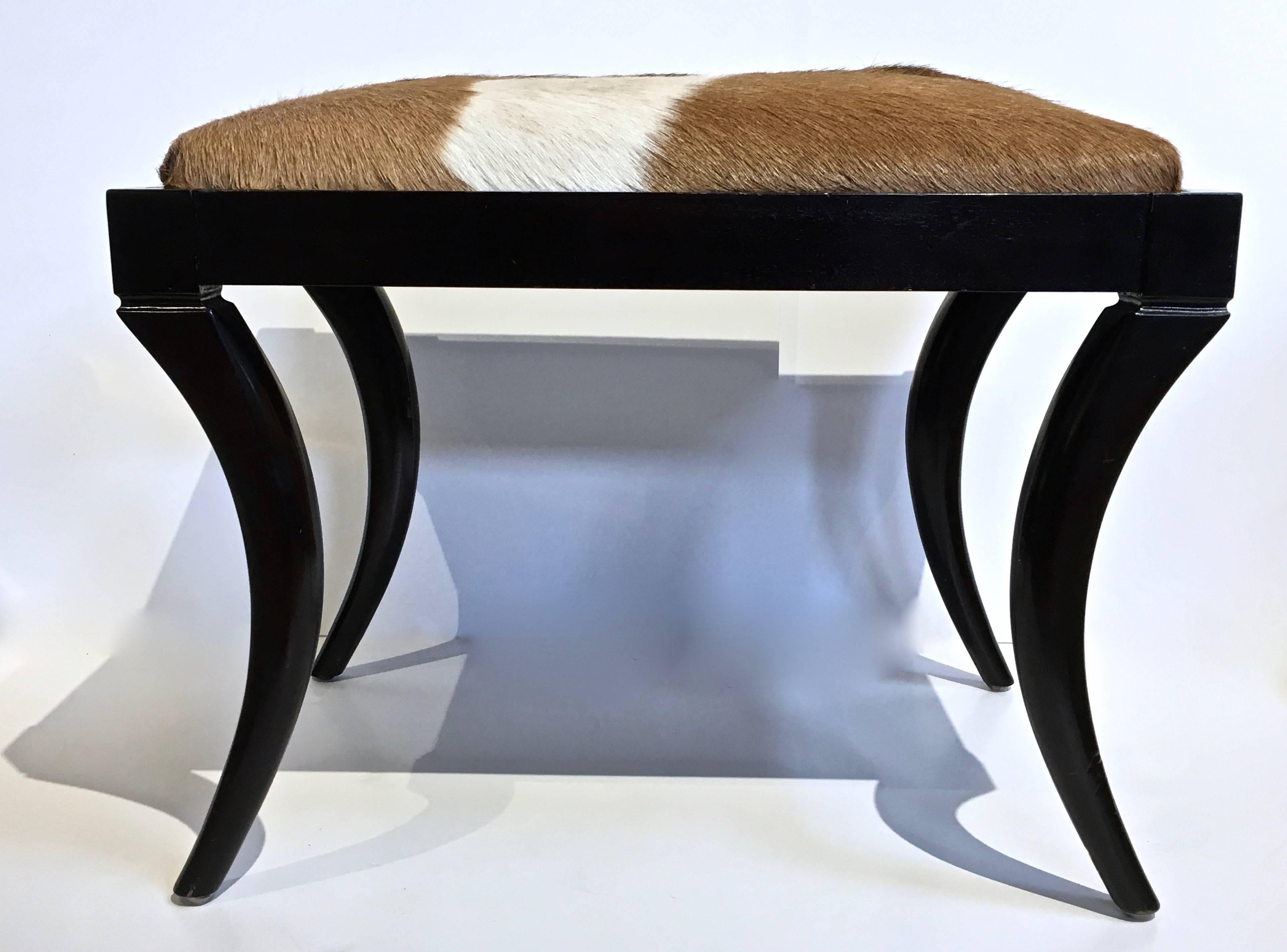 Upholstered pony skin hide bench on ebonized frame with elegant Saber legs.