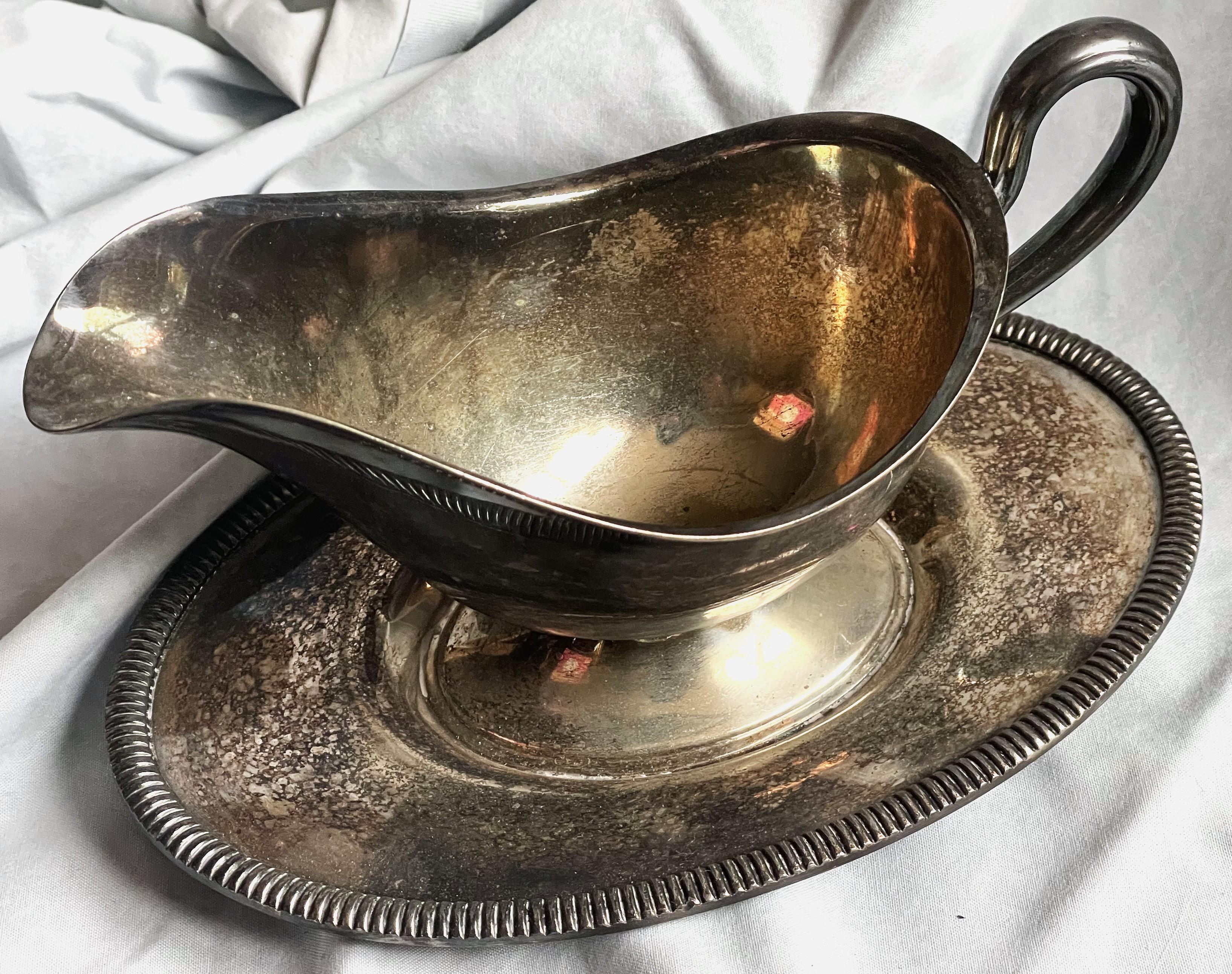 Il s'agit d'une saucière en argent EPNS avec un dessous de plat. Le dessous de plat présente un décor classique de nervures en relief sur le pourtour et la poignée est dotée d'une rainure de part et d'autre, sinon la saucière est tout simplement
