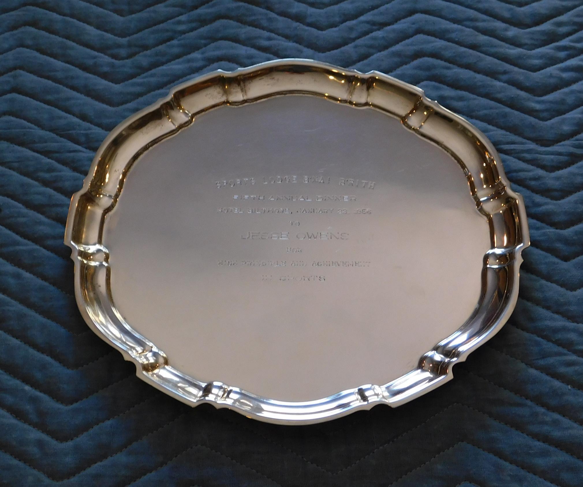 A Poole sterling silver Chippendale tray. 
The round tray has a molded and segmented border with an annotation at the center. 
The annotation reads: “Sports Lodge B’Nai B’Rith. Fifth annual Dinner. 
Hotel Biltmore, January 23, 1956. 
To Jesse Owens