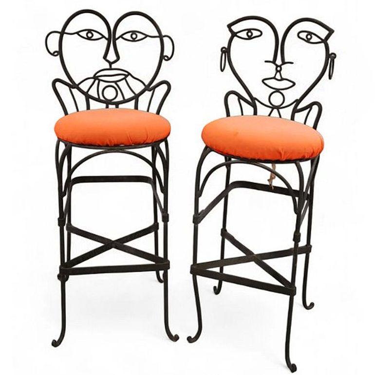 A pair of Pop Art wrought iron bar stools in the style of John Risley, each with an orange padded seat The intricate Mid-century metalwork features abstract, whimsical forms, blending functionality with artistic flair. The chairs' playful,