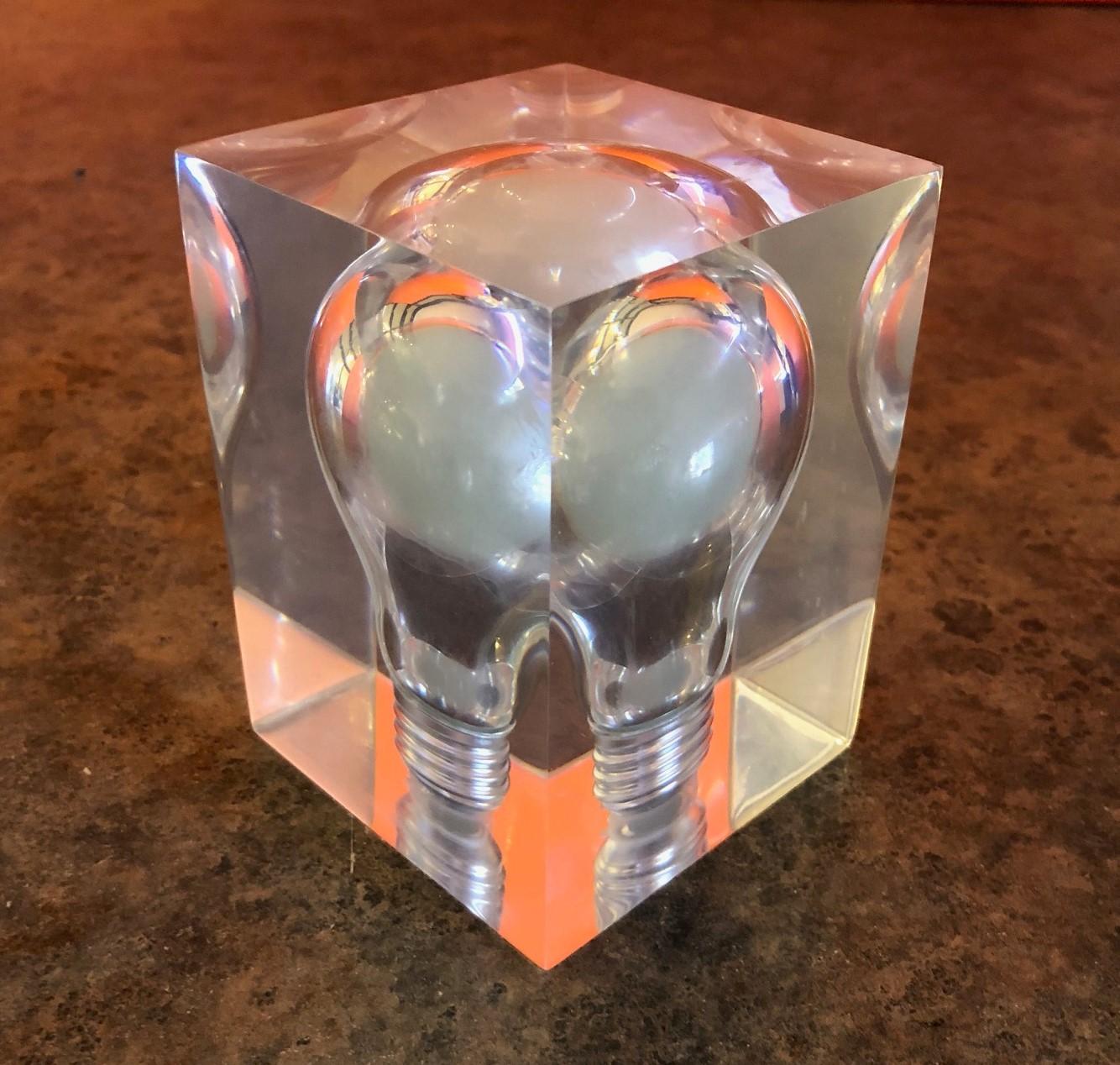 Haunting phosphorescent light bulb encased in a Lucite cube by French artist Pierre Giraudon, circa 1970s. The sculpture / paperweight glows in the dark and looks as though the bulb is floating in midair. Amazing 