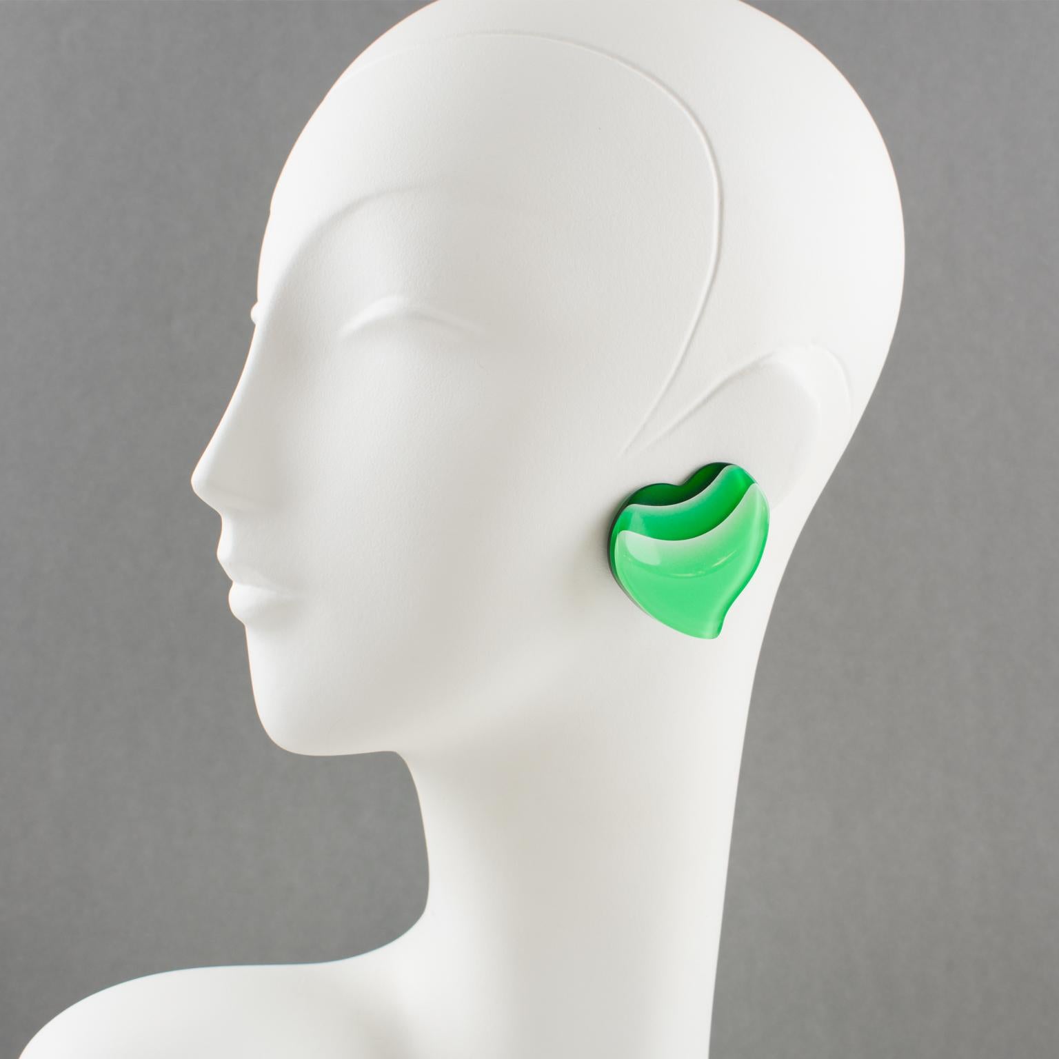 Lovely 1960s oversized Lucite clip-on earrings. Features a large carved heart shape with lamination. Transparent forest green color background shaded to green grass and aqua green bright colors. There is no visible maker's mark.
Measurements: 1.57