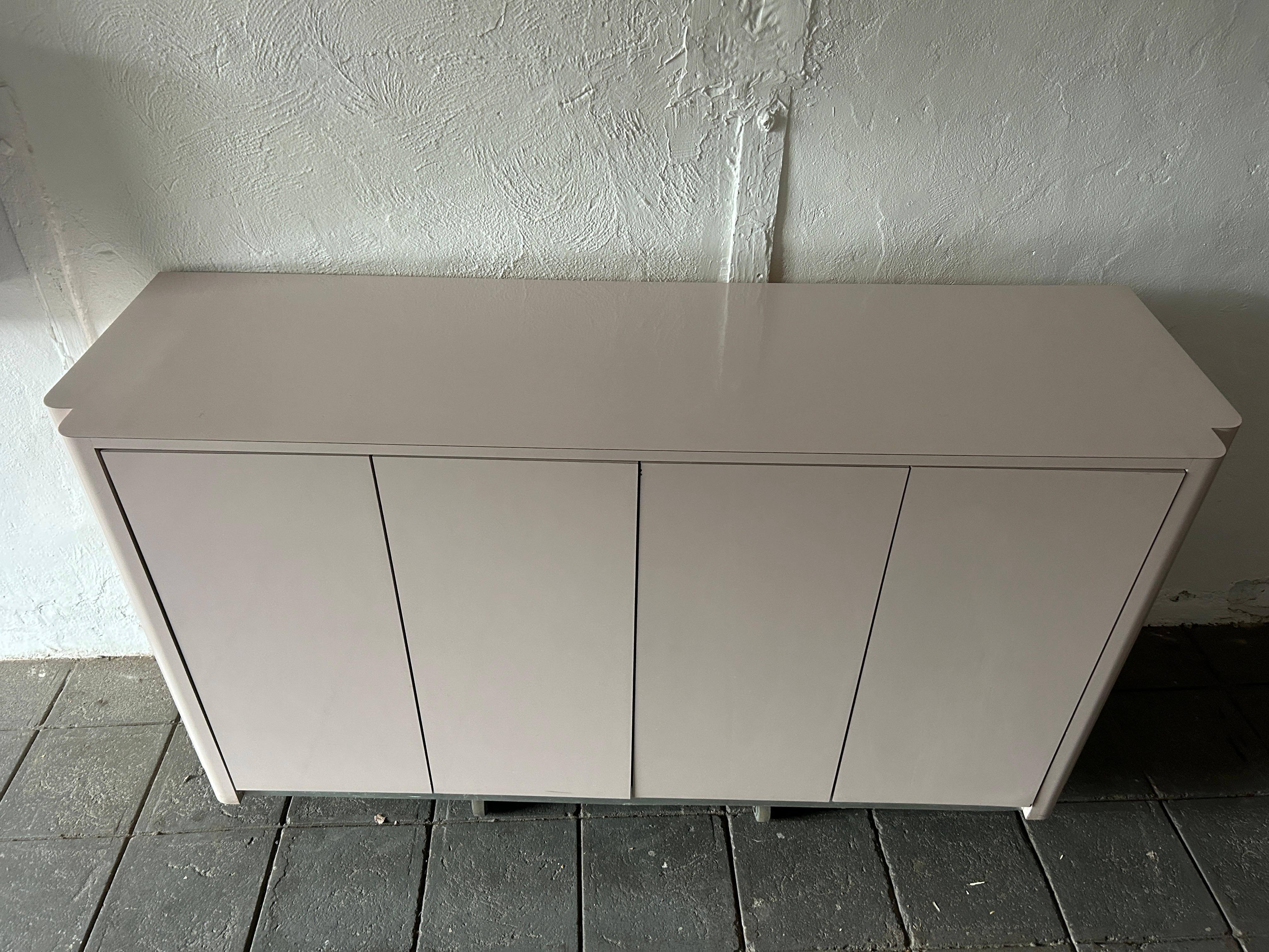 Pop art post modern 4 door muave pink credenza sideboard. Very light muted muave pink laminate credenza custom made circa 1980 has 4 cabinet doors with magnetic catches. Behind the doors are (4) adjustable shelves and (1) flatware drawer. Ready for