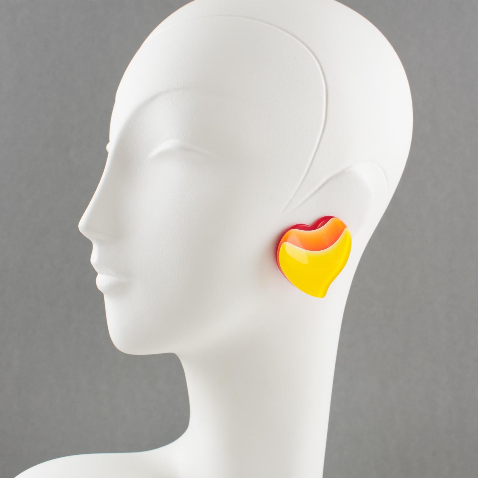 These lovely Lucite clip-on earrings feature a large carved heart shape with lamination. The bright red background is shaded with bright orange and yellow. There is no visible maker's mark.
The earrings are in good condition, with a light shape