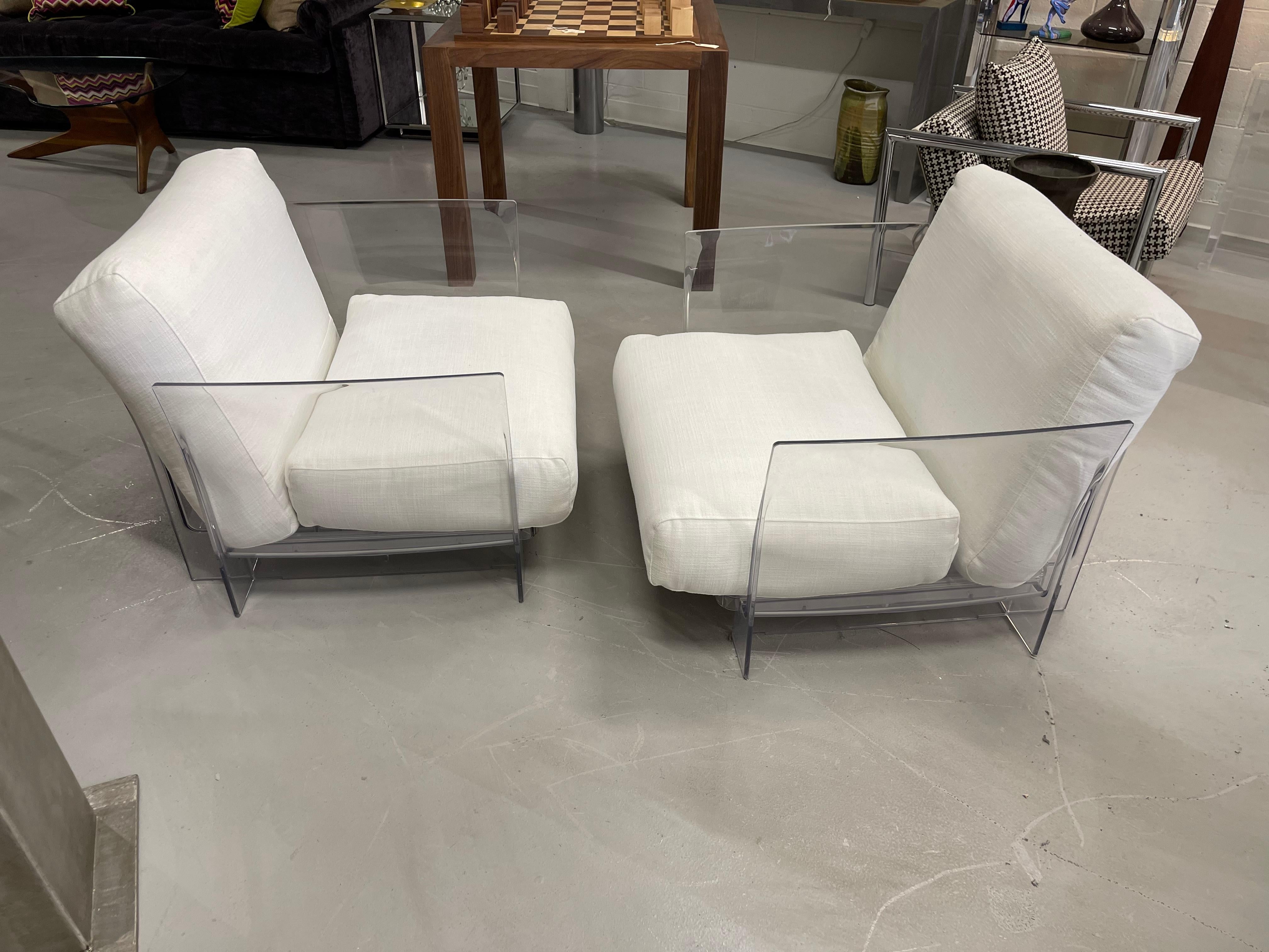 A pair of Outdoor chairs by Kartell designed by Piero Lissoni with Carlo Tamborini. They each have two cushions covered in a white Sunbrella fabric. There can obviously be used indoors as well. Clear acrylic frames each marked on the interior. In