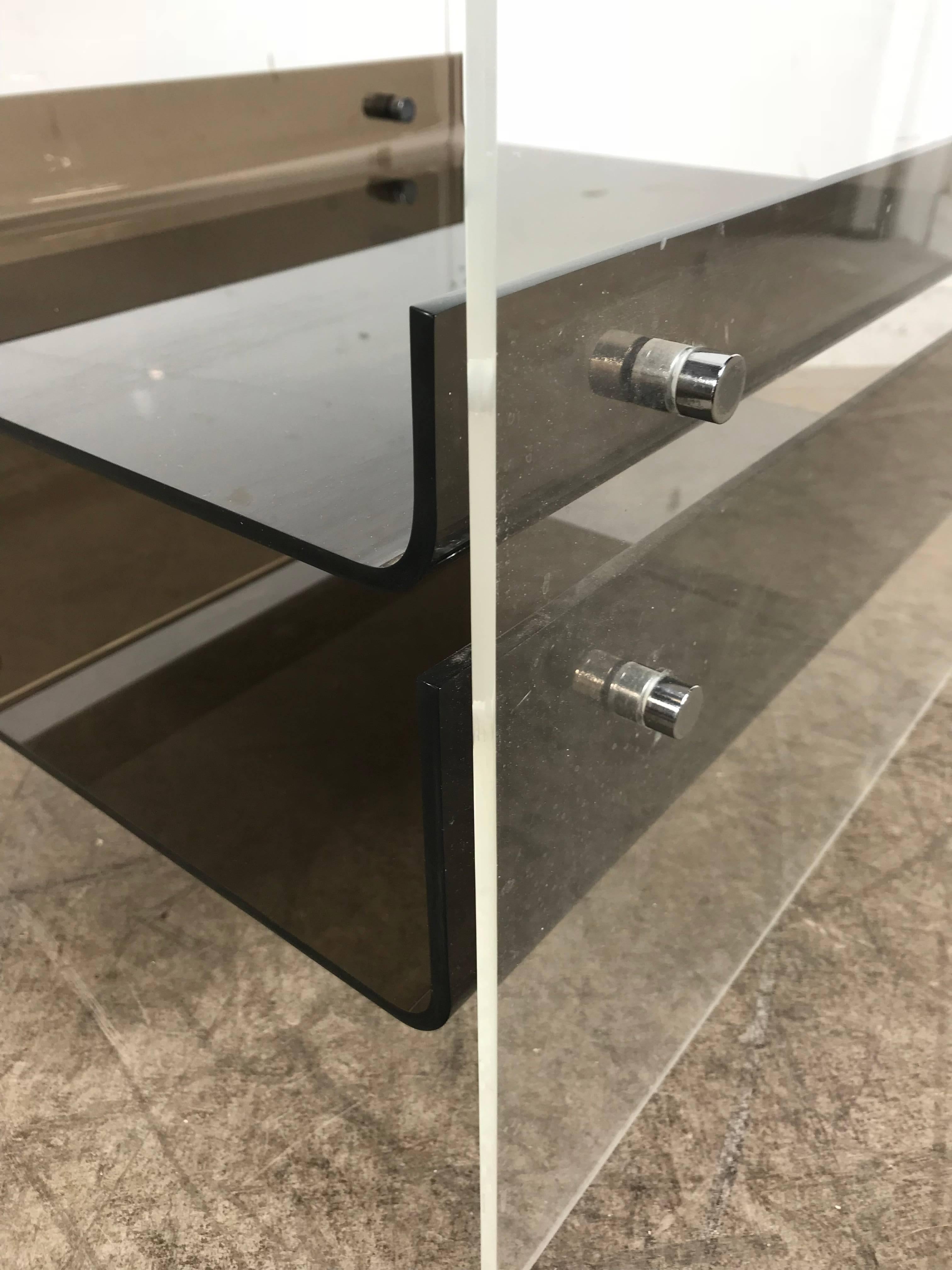 This acrylic side table with its striking Minimalist look is attributed to Neal Small, using the same chrome hardware seen on his other designs, transparent table made from a single piece of acrylic with a pair of upturned smoke shelves.