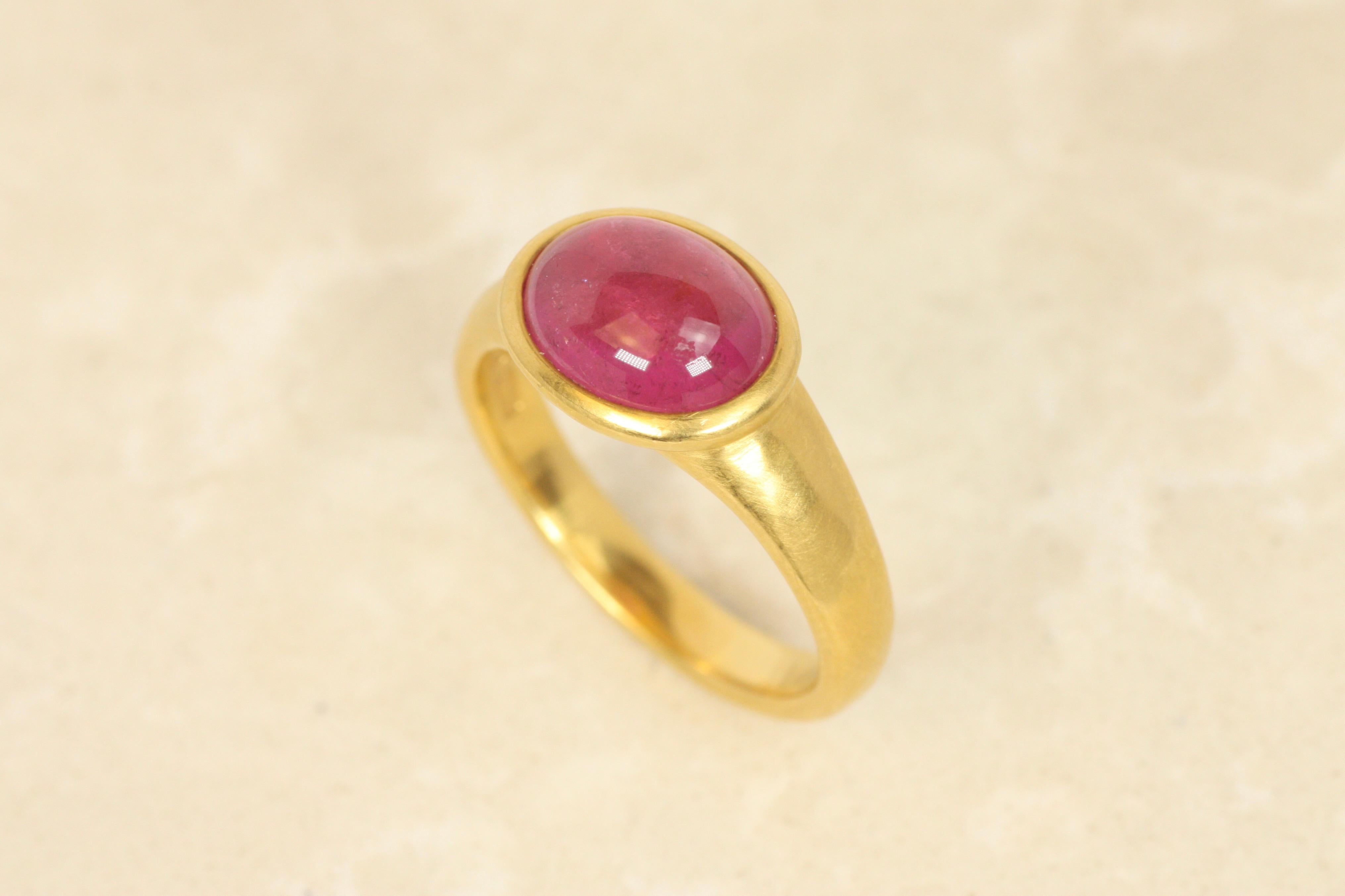 Dieser verspielte und doch raffinierte Ring zeigt einen rosafarbenen Turmalin im Cabochon-Schliff, der Farbe und Charme versprüht. Der mohnrosa Edelstein ist in 22-karätigem Gelbgold gefasst und hat ein gehämmertes, mattes Finish, das ein gesundes,