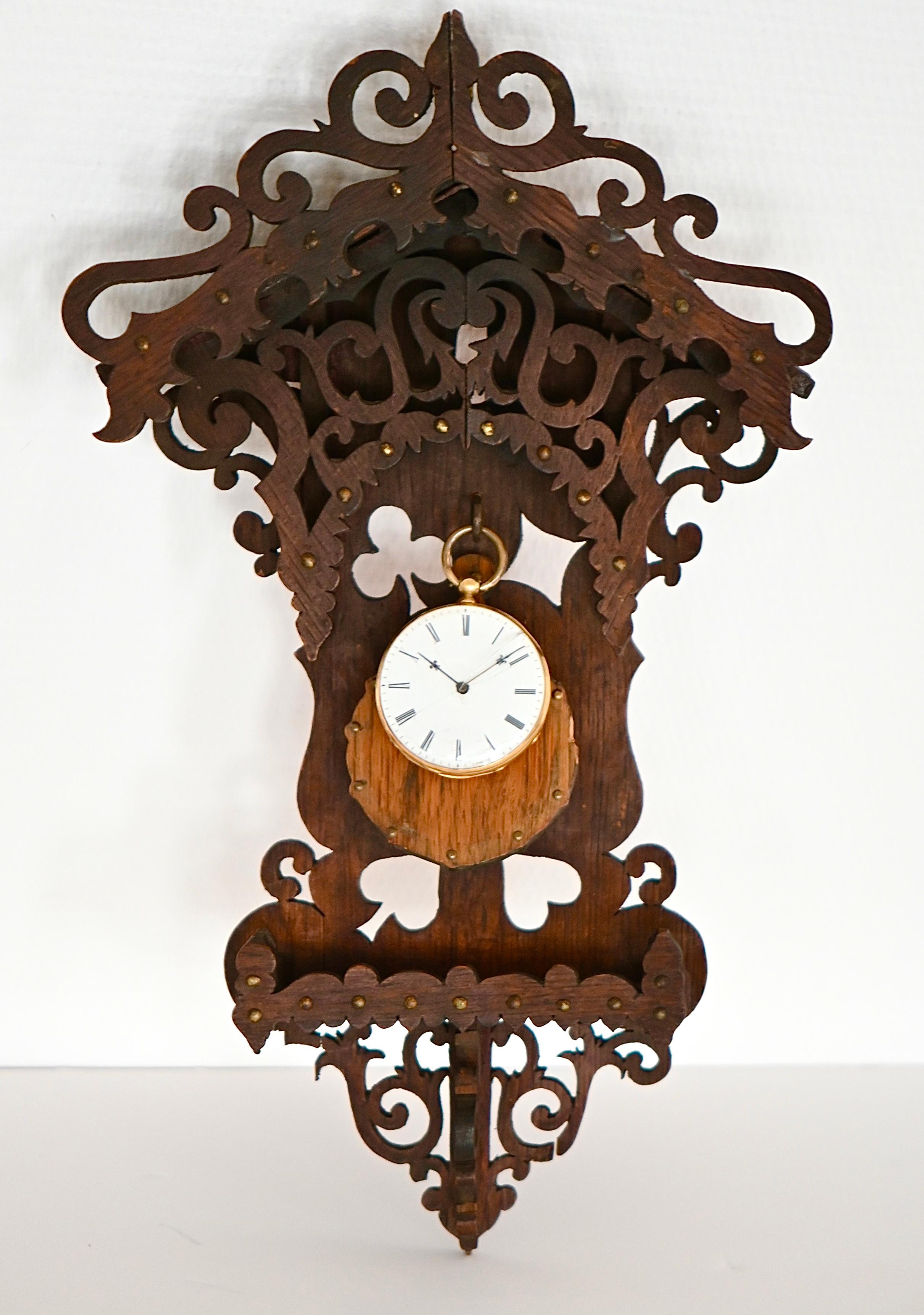 Scopri un portaorologio dal fascino rustico e autentico, tipico dello stile dell'arte popolare. Intagliato a mano con notevole meticolosità, presenta motivi traforati di fiori, cuori, picche e scacchi, che simboleggiano fortuna ed eleganza senza