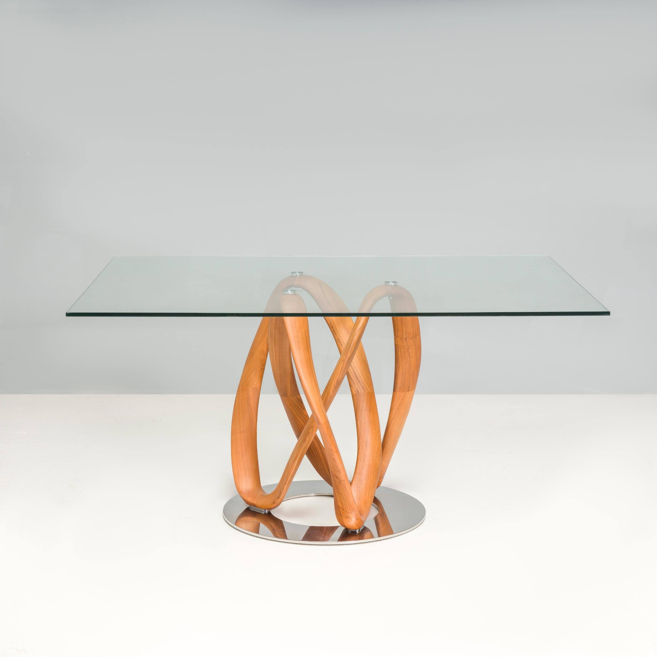 Der Infinity-Tisch wurde 2009 von Stefano Bigi für Porada entworfen und wird in aufwändiger Handarbeit in der Porada-Werkstatt in Brianza hergestellt. Der Tisch besteht aus einem Untergestell aus Canaletta-Walnussholz mit einer gedrehten Form, die