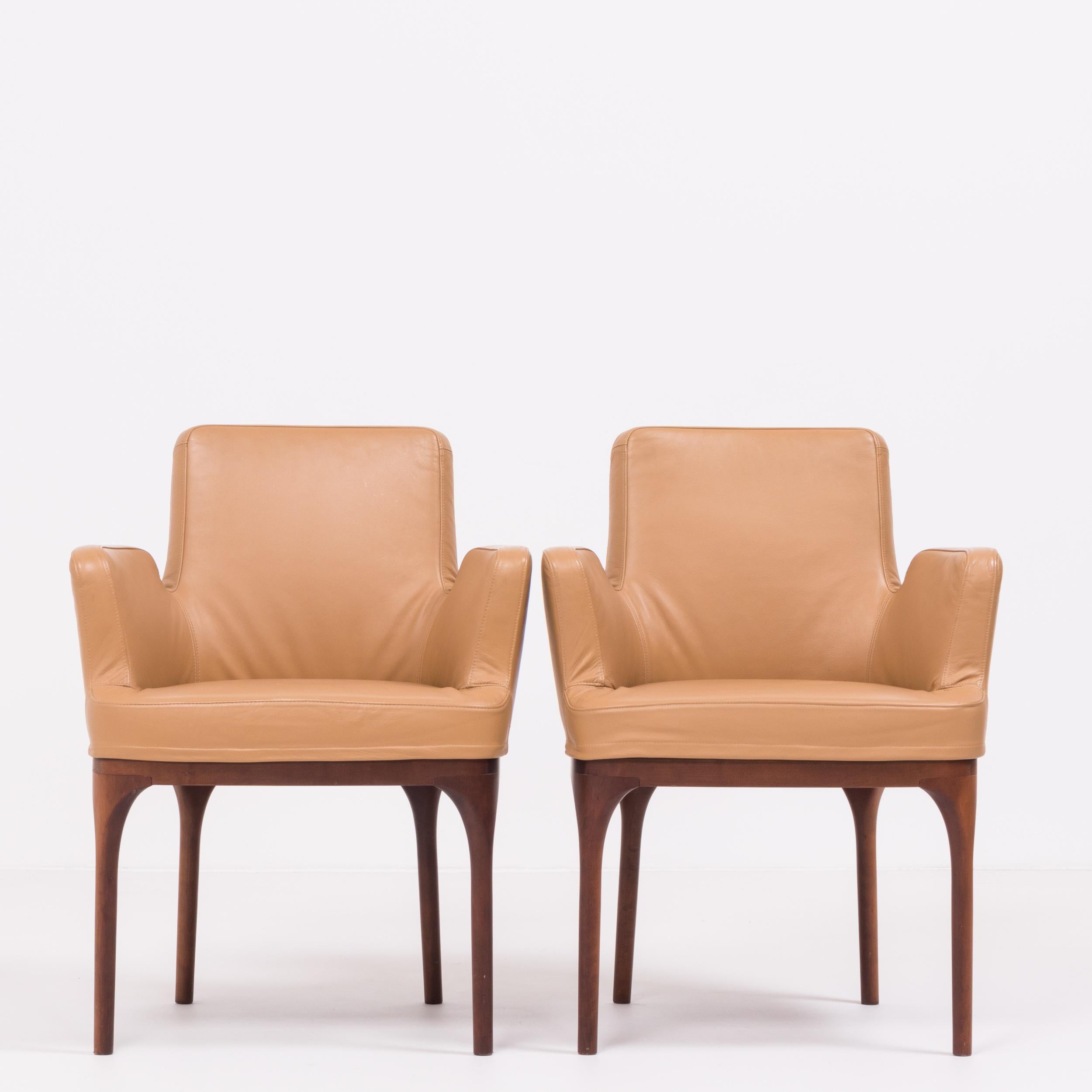 A stunning example of Mid-Century Modern design, this set of two dining chairs were manufactured by Porada and are in excellent condition.

With a deep bucket shape and squared arms, the chairs are upholstered in soft toffee brown colored leather