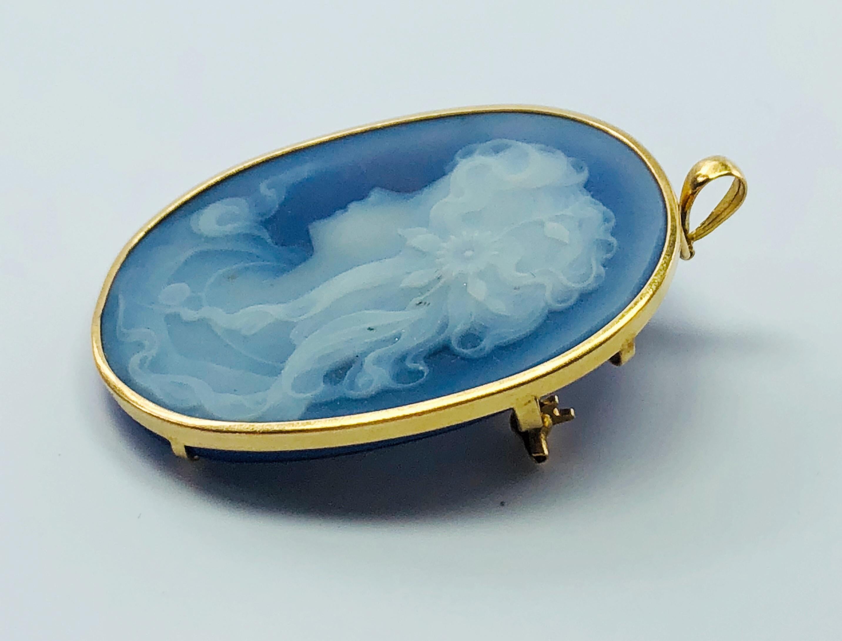 This absolutely gorgeous cameo is in the Wedgewood Style! Profile of a young woman with long curls down her neck and a beautiful flower in her hair. It is hand carved porcelain that is set in an 18K yellow Gold setting. This beautiful piece can be