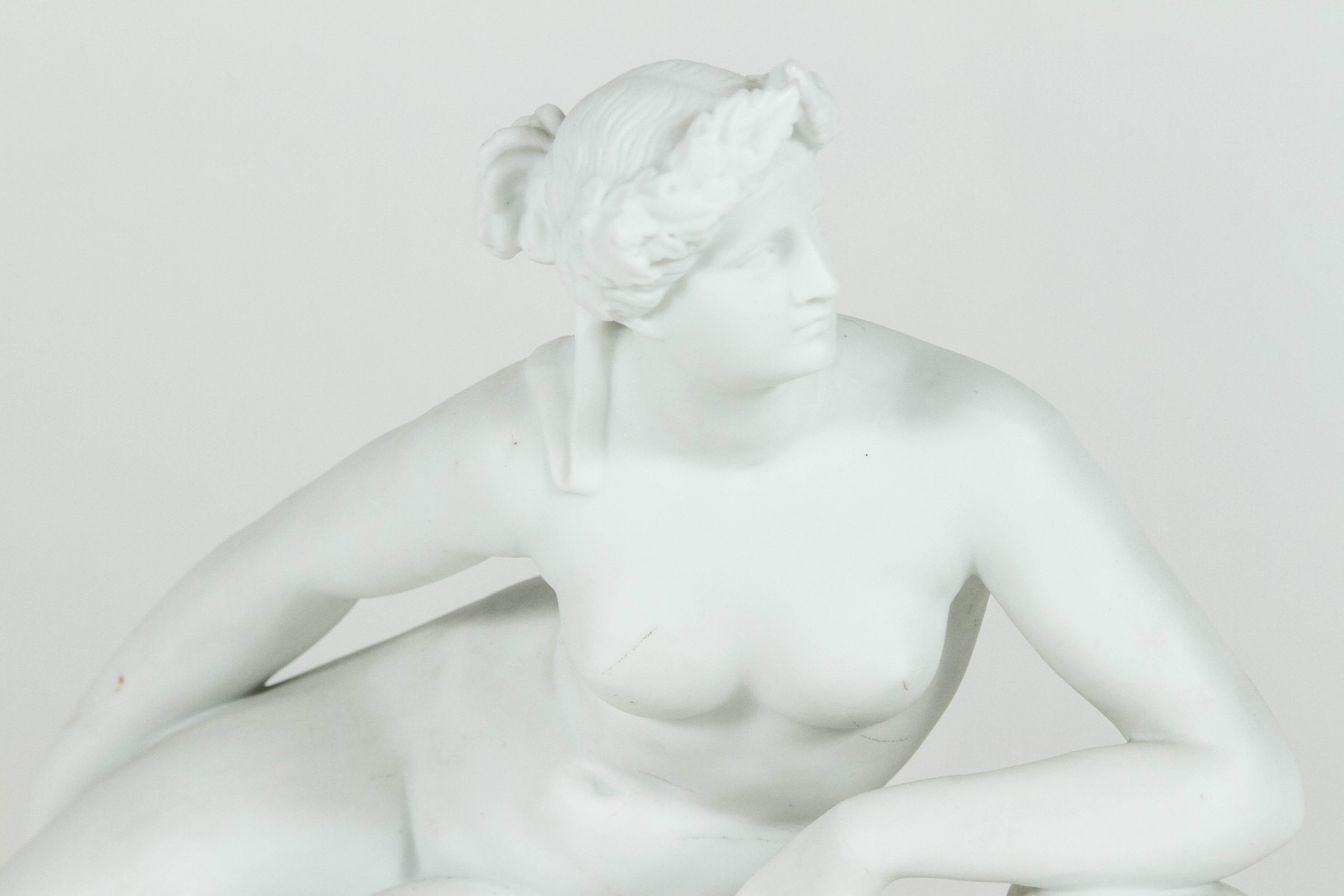 Exquise sculpture figurative en porcelaine représentant une femme nue aux traits gréco-romains classiques, allongée au sommet d'une panthère. La femme arbore une coiffure complexe qui était très populaire chez les femmes romaines. La panthère porte