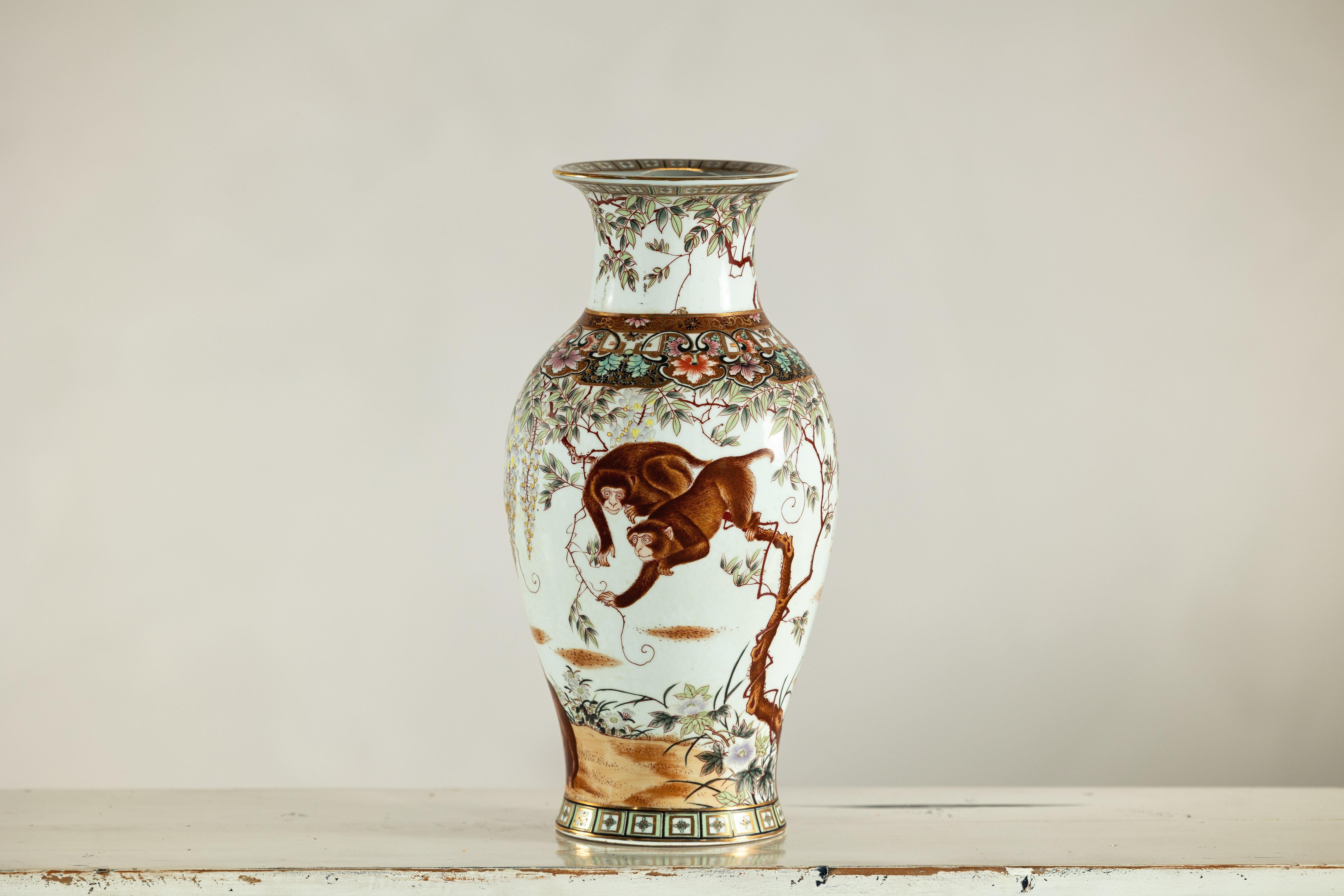 Questo vaso in porcellana splendidamente dipinto a mano raffigura una vivace scena di scimmie che si dondolano tra delicati rampicanti di glicine, un motivo che nell'arte cinese simboleggia intelligenza, curiosità e longevità. I toni caldi del