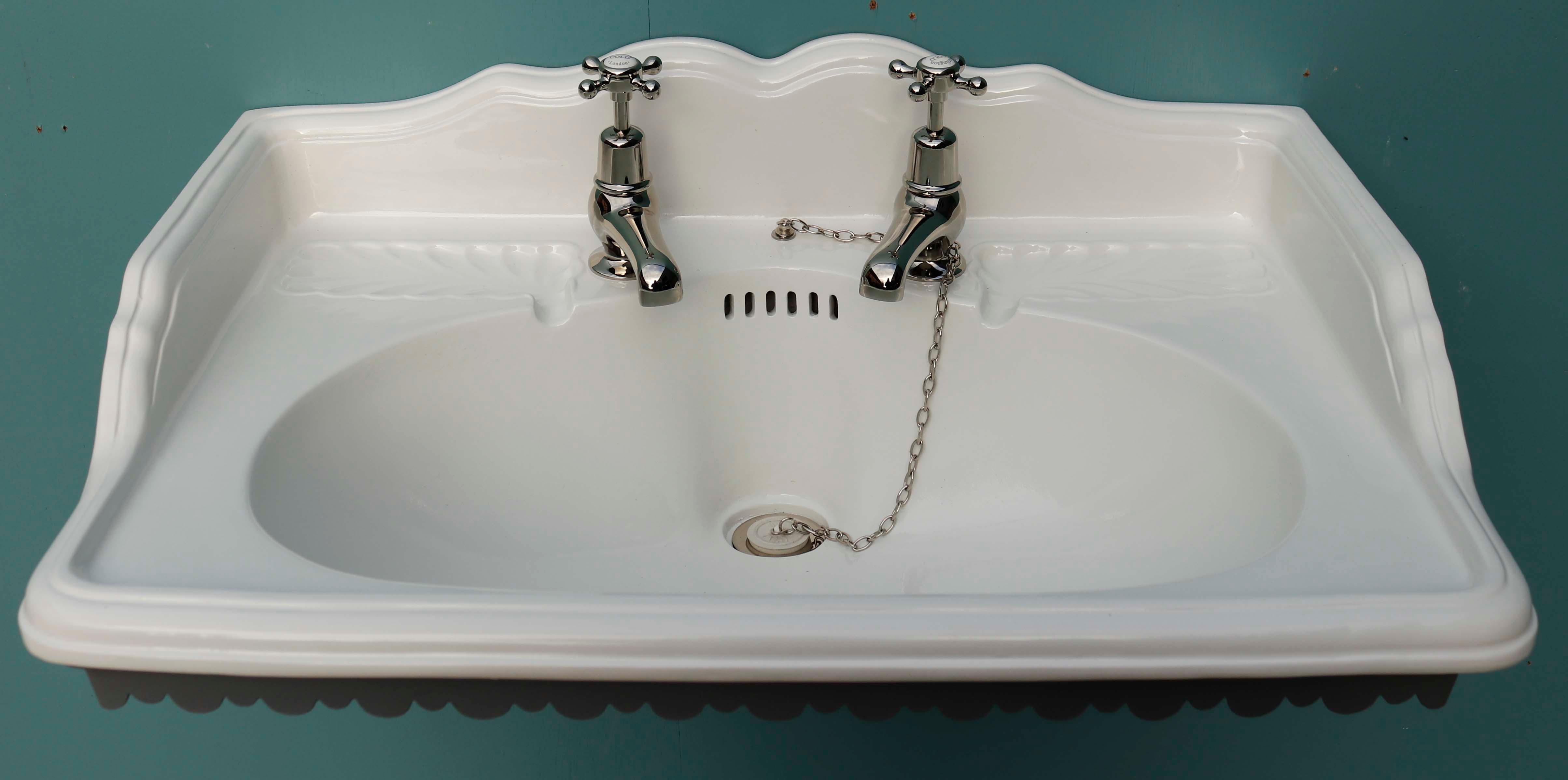 Porcelain sink with decorative bracket. A completely restored basin with added traditional style taps. The bracket has been shot blasted and painted with grey paint.