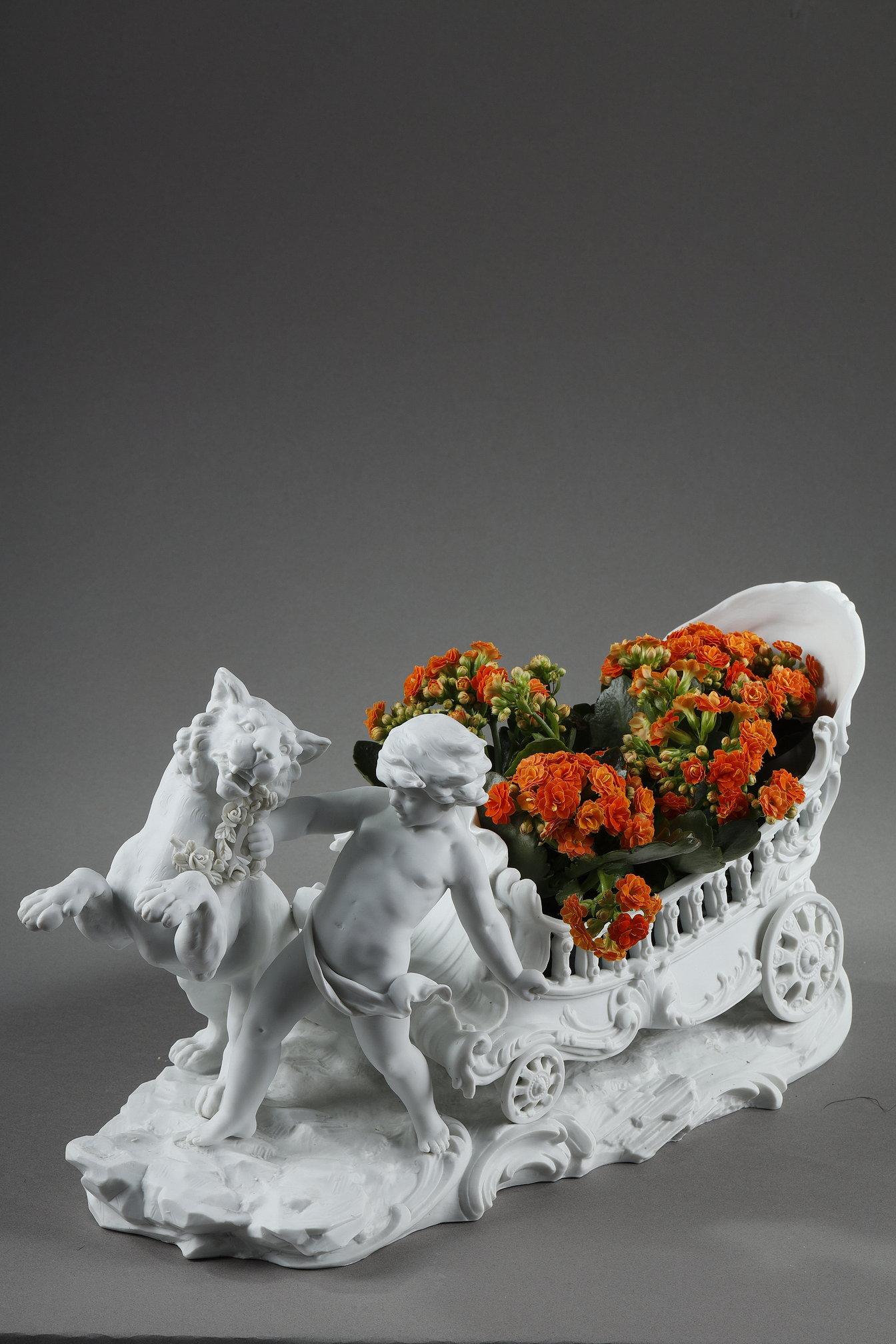 A large biscuit-type white porcelain basket featuring a putto guiding a prancing fawn adorned with a garland of flowers, harnessed to a richly molded chariot with rocaille decoration, resting on a base simulating rocky ground. 

The basket, with its