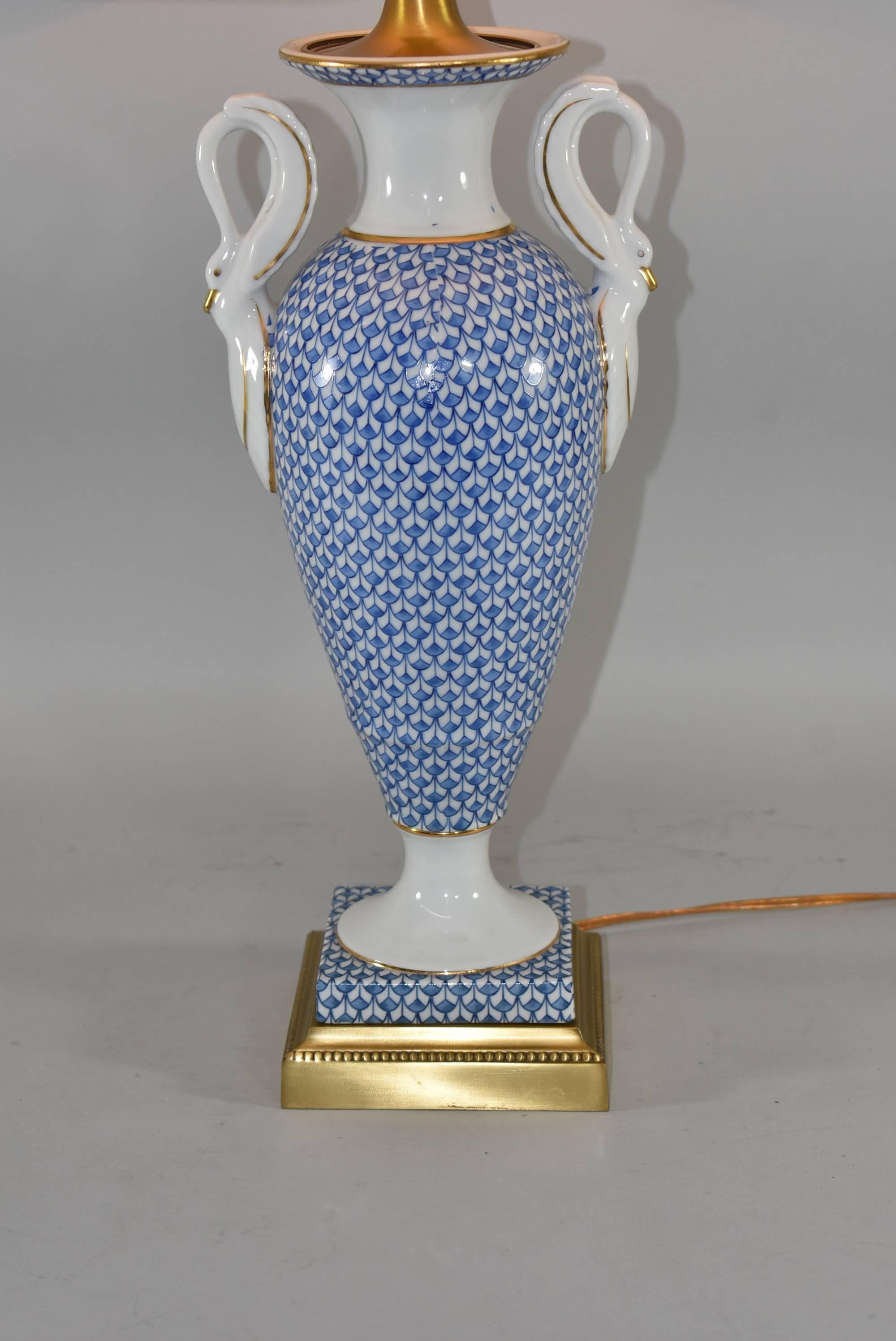 An unusual porcelain table lamp by Frederick Cooper. This beautiful lamp features a trophy form with swan handles and a blue fish scale surface. This sits on a heavy cast brass base with beaded trim and has a three way switch.