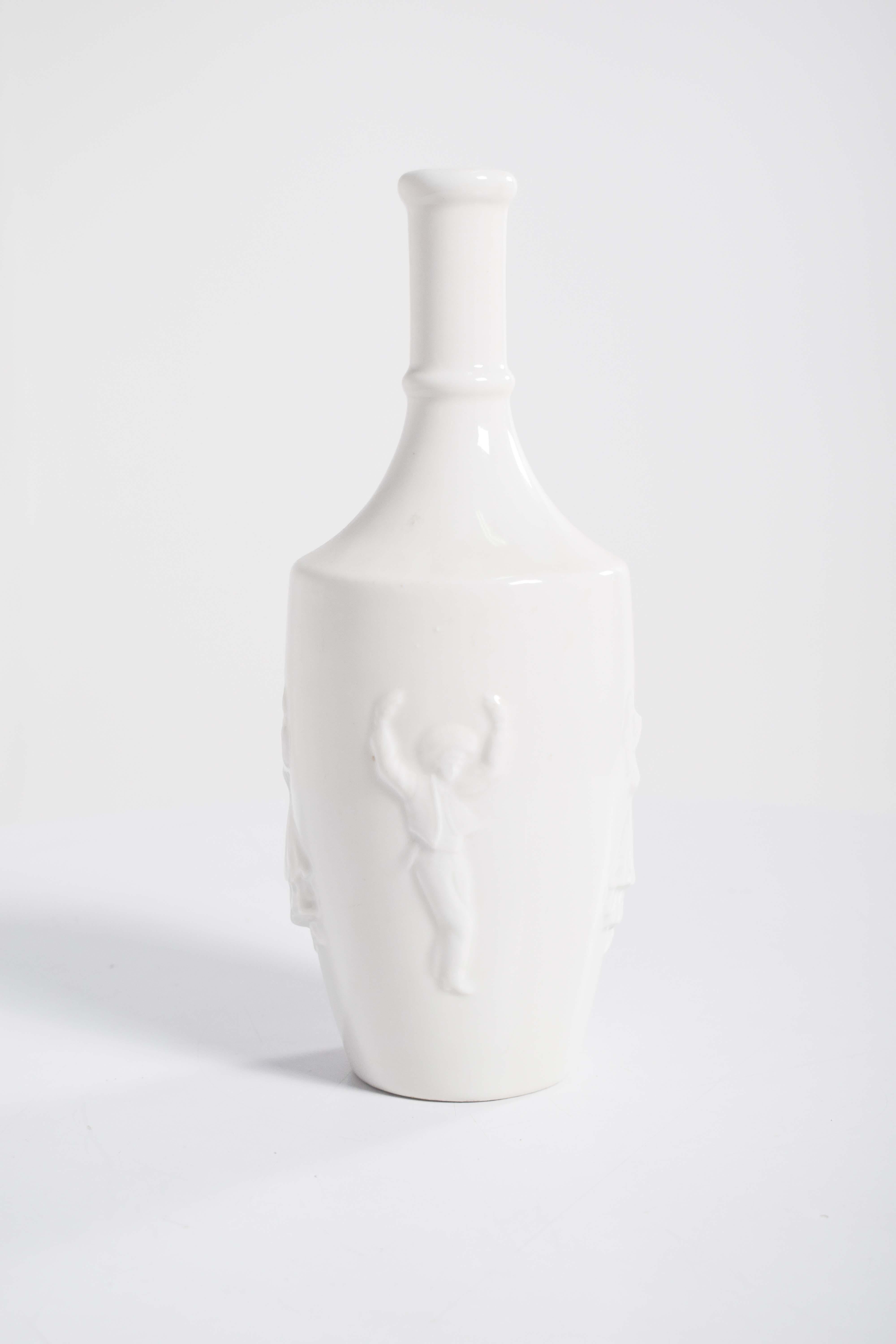 Una botella de porcelana con esmalte blanco, decorada con figuras danzantes en relieve, es una pieza de artesanía llamativa y elegante. La botella está hecha de porcelana lisa y brillante, con un lustroso revestimiento de esmalte blanco que le da un
