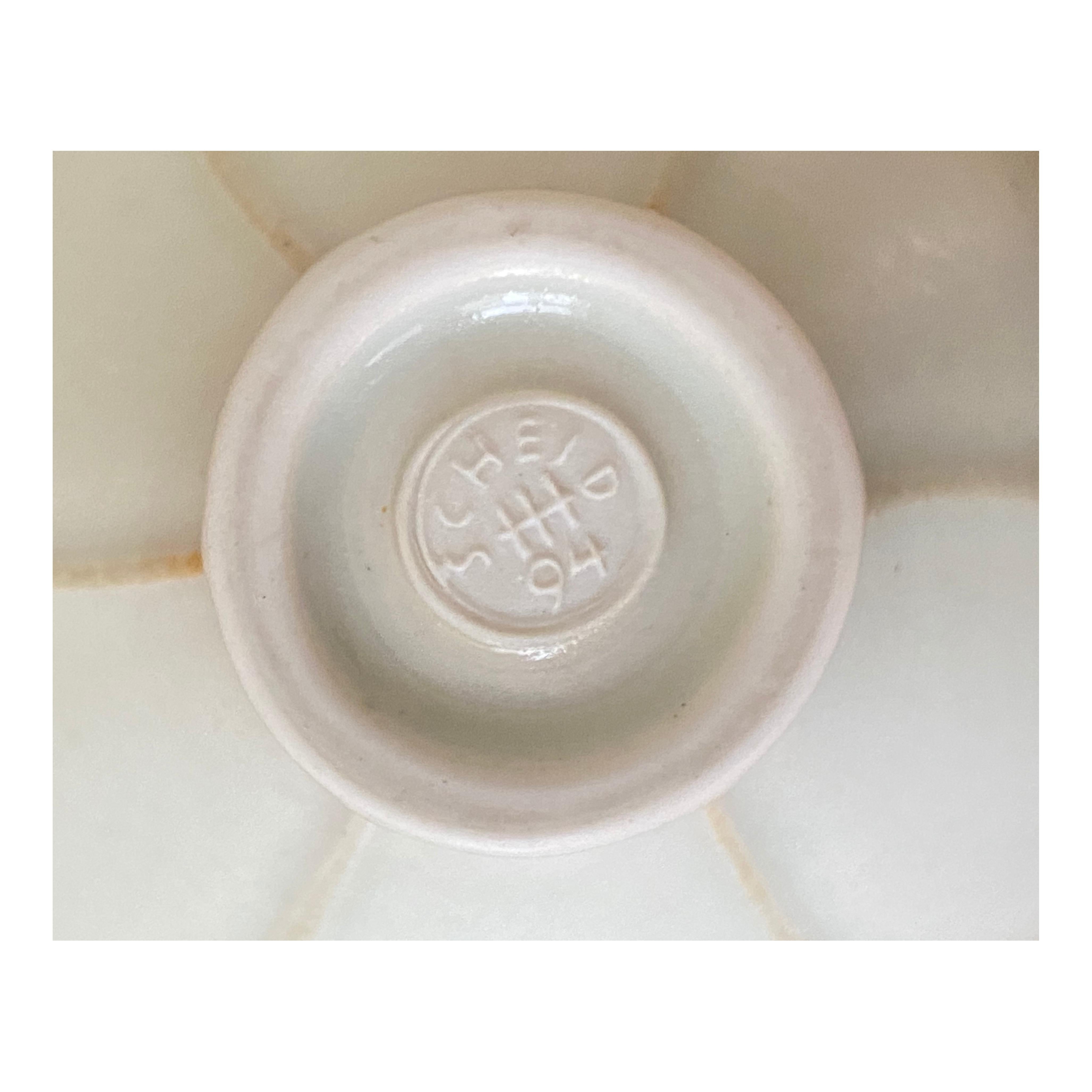Hand thrown porcelain bowl in silky matte white and celadon colored glaze with petal rim in light pink

Marked with workshop mark and dated 1994 (stamp),

Germany.
  