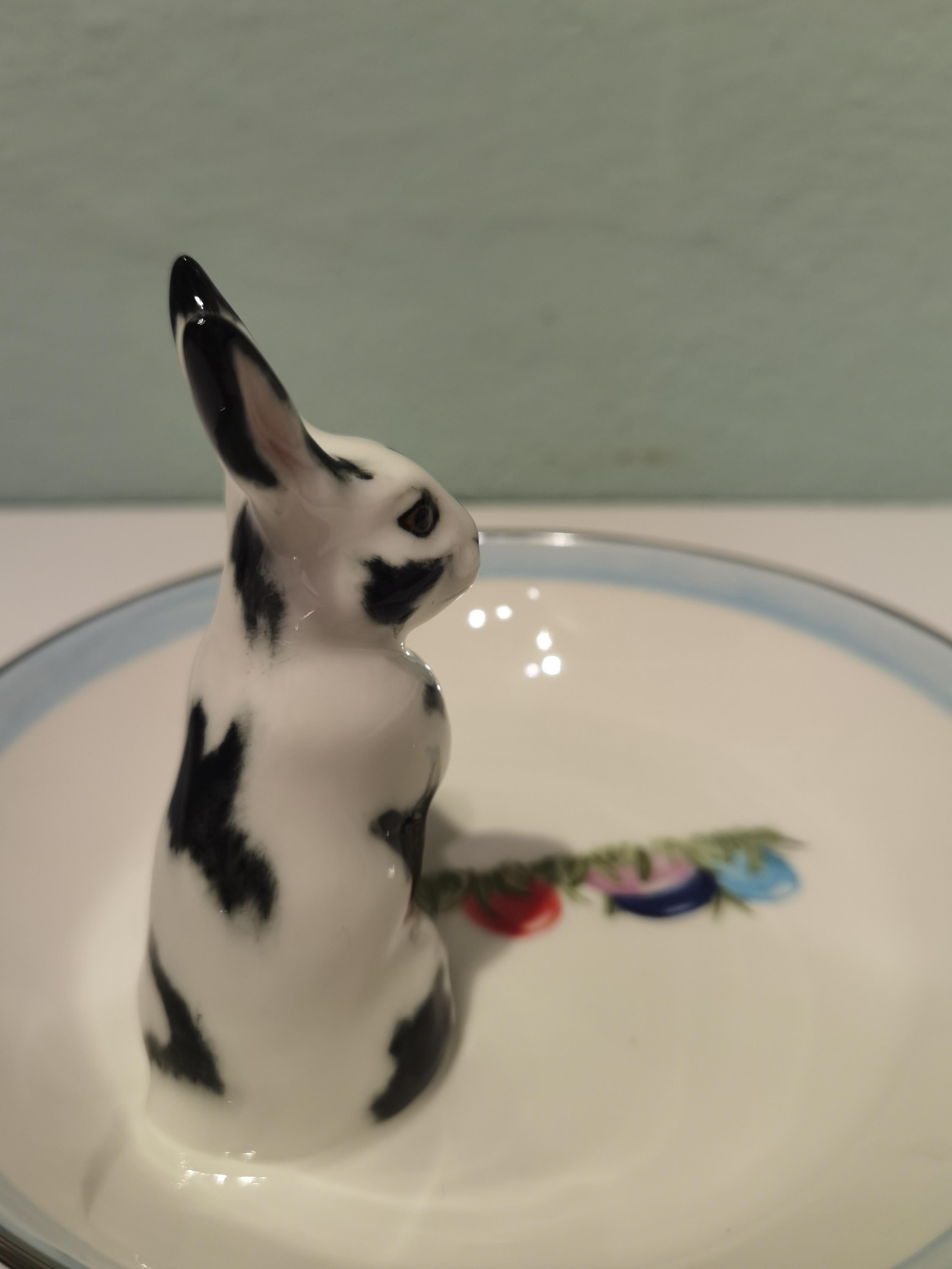 Completely handmade porcelain bowl with a hands-free naturalistic painted Easter rabbit in black and white colors. The rabbit is sitting at the side of the bowl with hand painted colored Easter eggs. Rimmed with a Fine platinum line. Handmade in