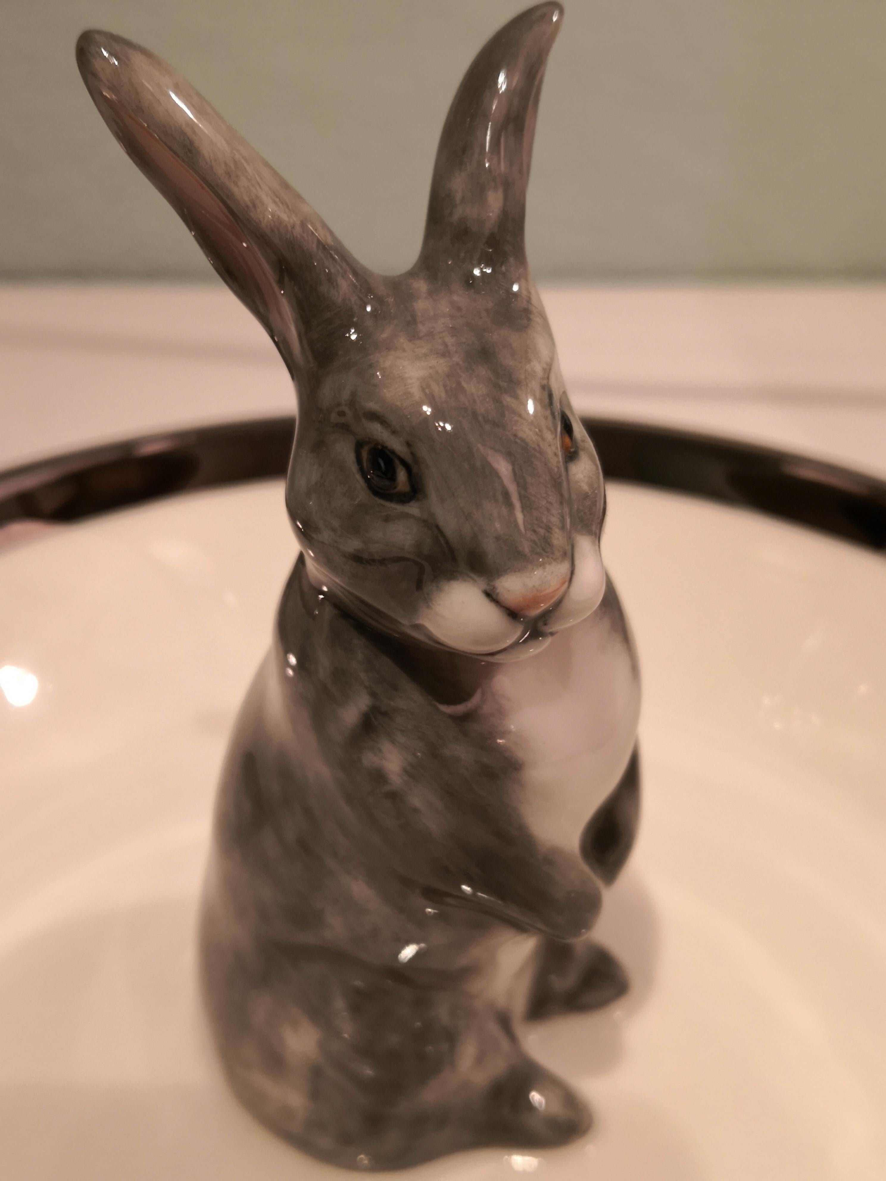 Bol en porcelaine entièrement fait à la main avec un lapin de Pâques peint de façon naturaliste dans des couleurs grises et blanches. Le lapin est assis au milieu du bol pour décorer les noix ou les bonbons autour de la figure. Bordé d'une fine