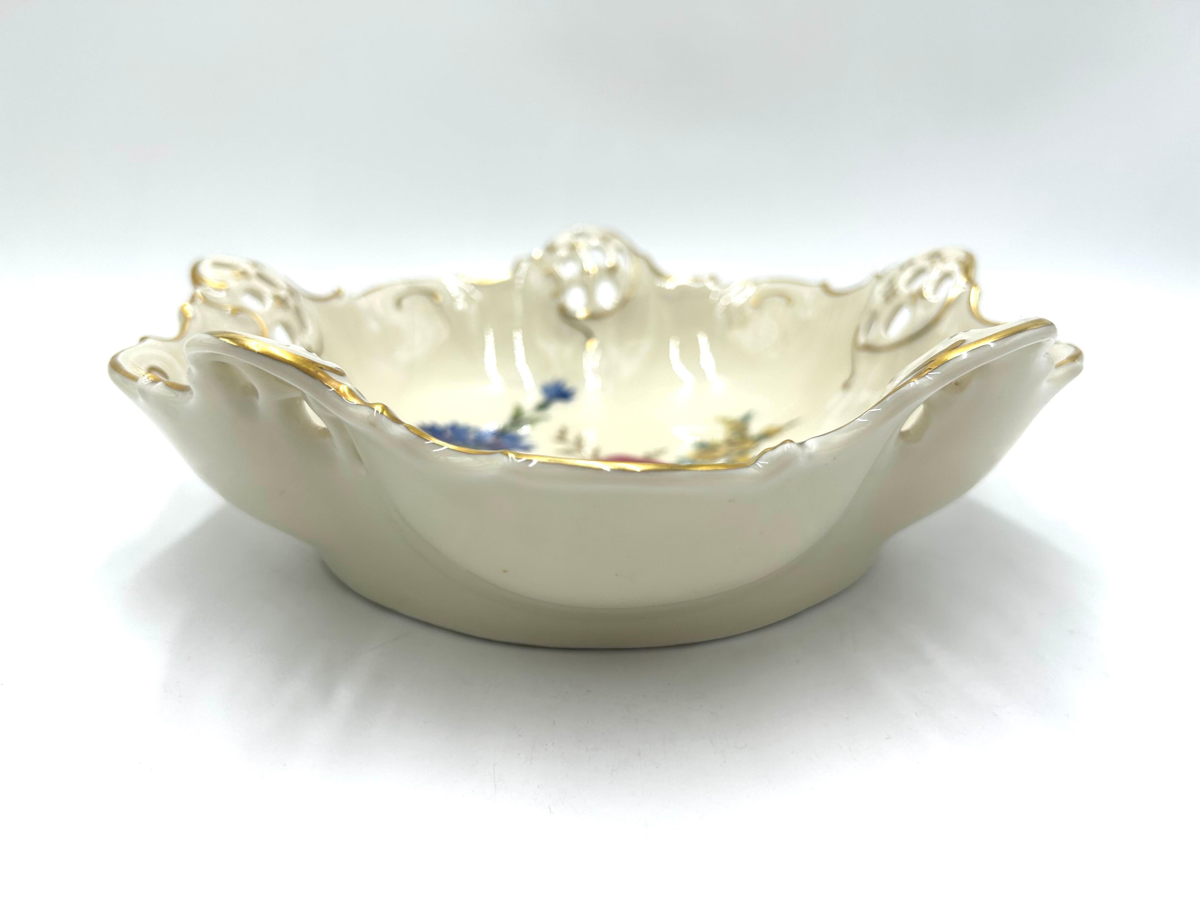 Porcelain openwork bowl made of ecru porcelain, decorated with gilding and a bouquet of flowers motif. A product of the valued German manufacturer Rosenthal. Signed with a mark from 1944.
The bowl has damage in the form of a hairline crack on one