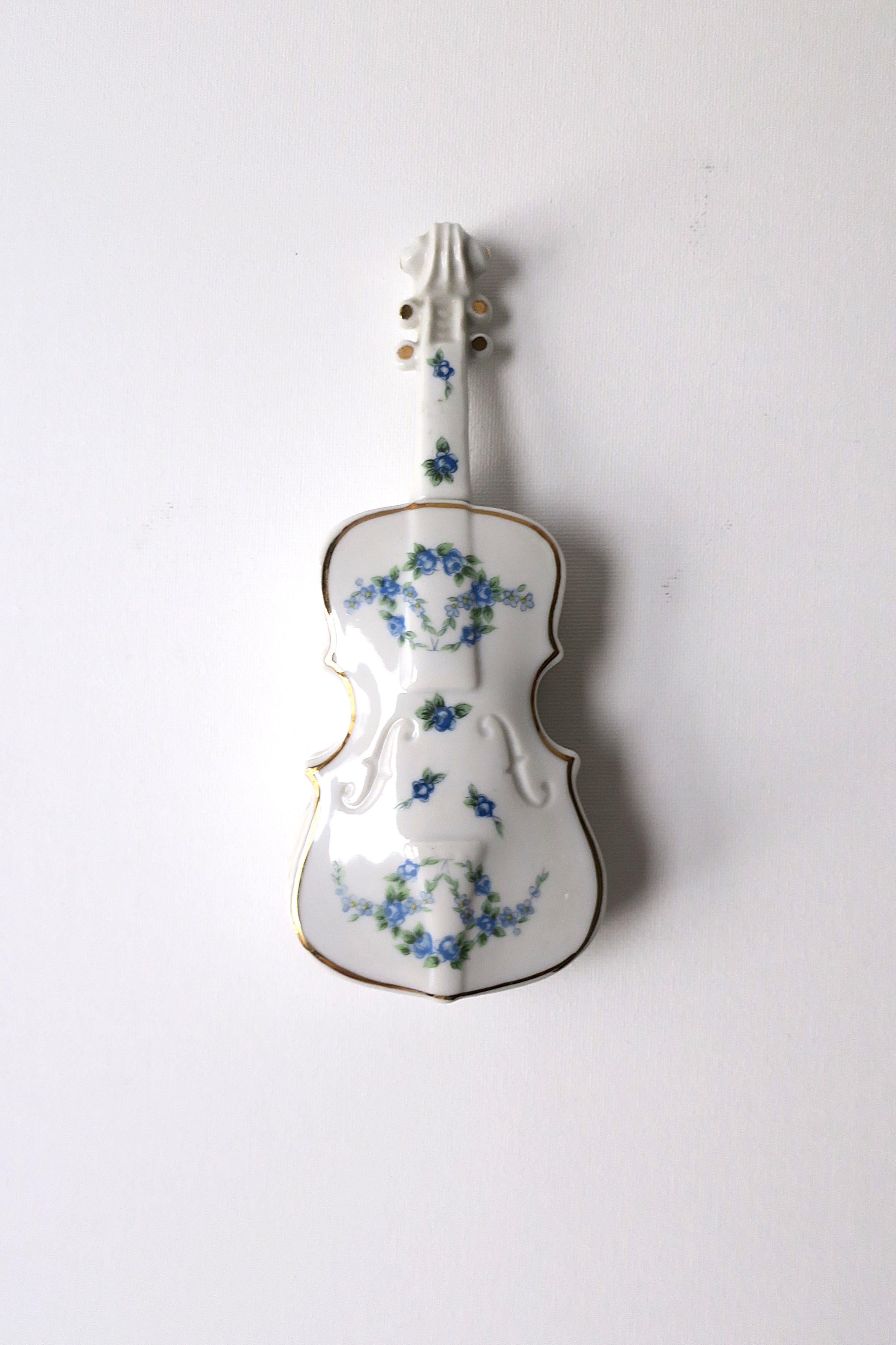 A white porcelain 'violin' box with blue and green floral 'Chintz' design, circa mid-20th century, 1960s. This violin shaped box, outlined in gold, has a blue flower and green leaf chintz design on top and sides, and a removal top lid revealing