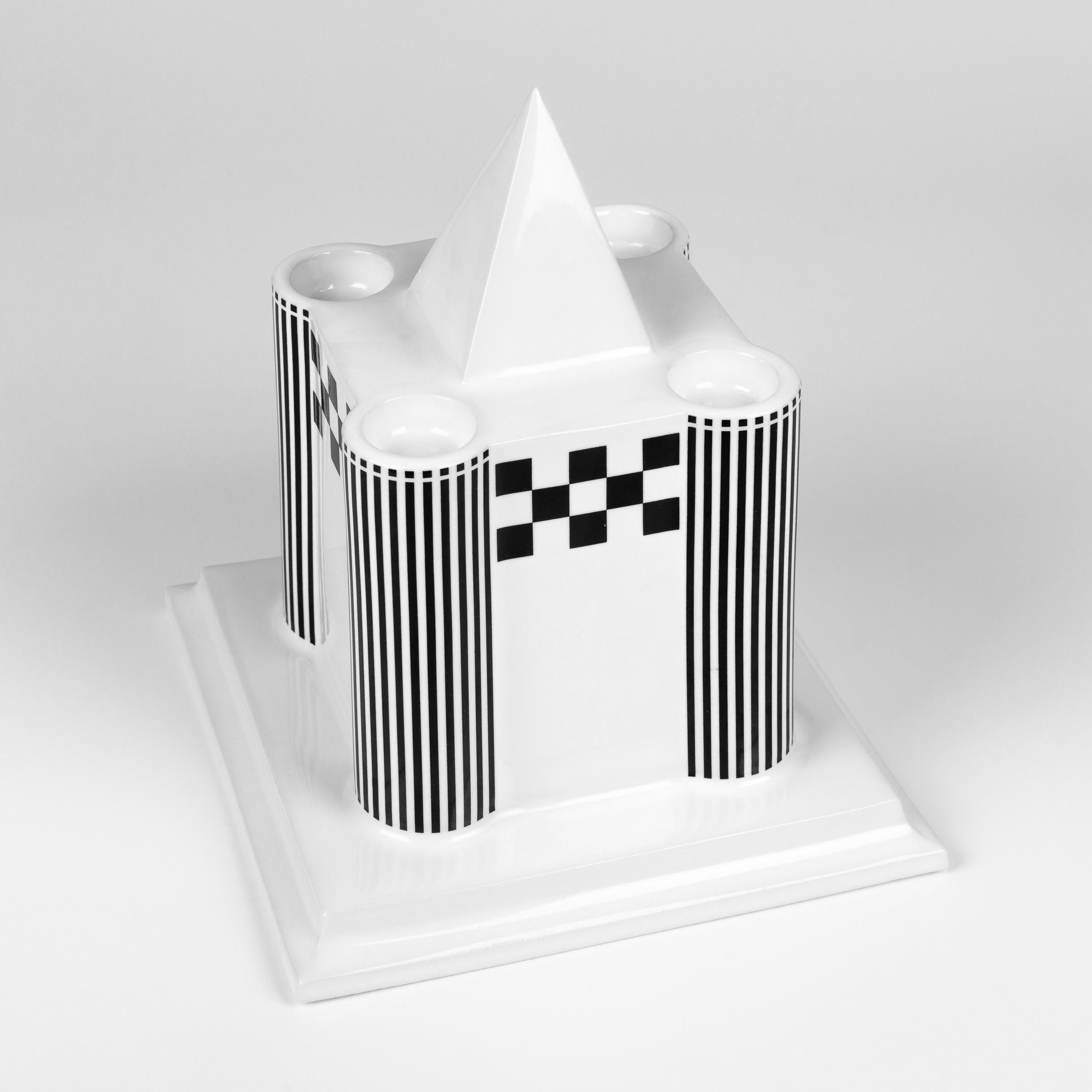 Austrian designer Heide Warlamis is the creator of this architectural postmodern candleholder for four candles made in the 1980s. It is part of her cult series called the Vienna Collection where each piece refers to building types. In this piece,